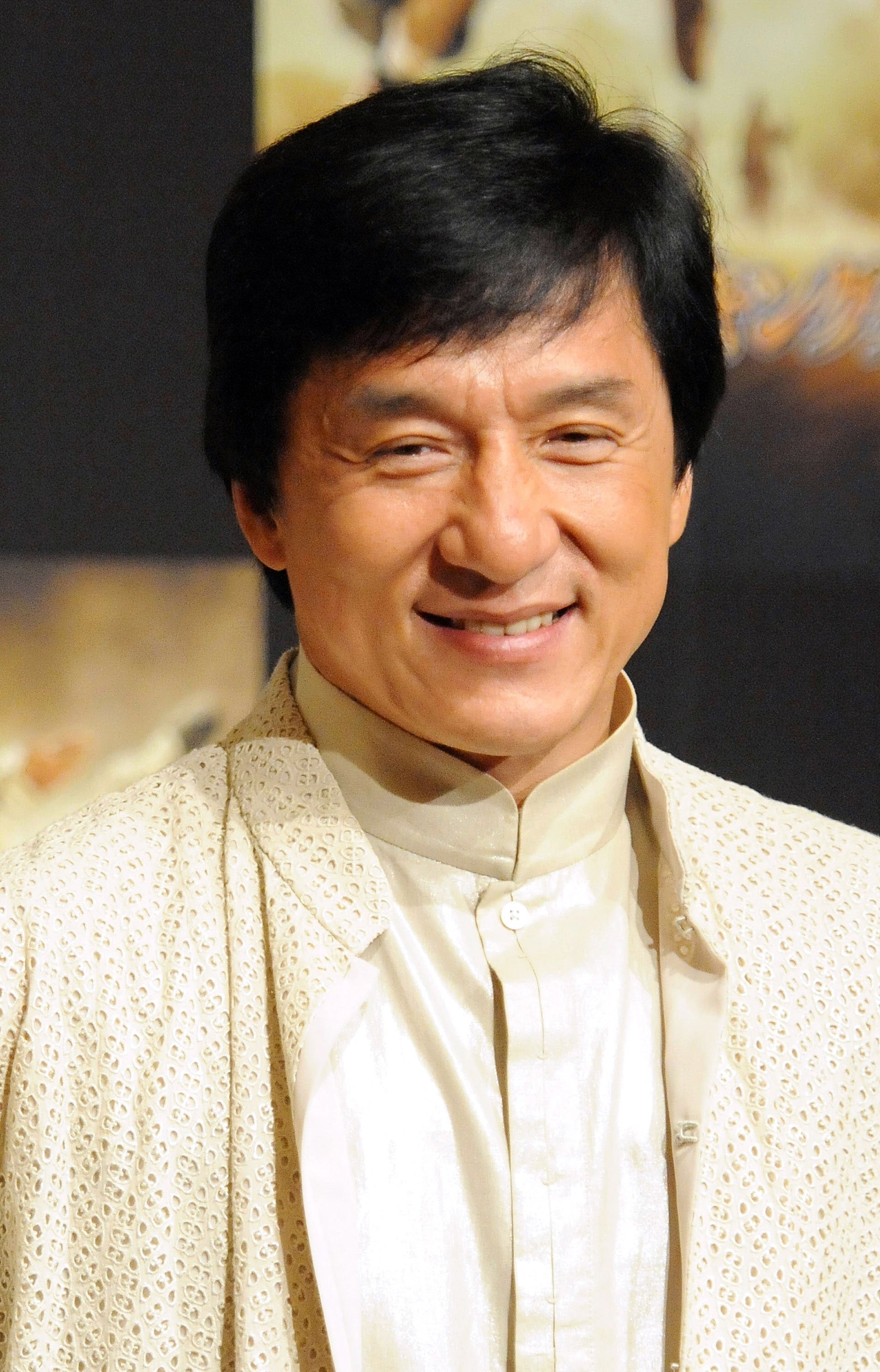 I don't know who this is, but it's a person smiling, wearing a textured jacket over a light shirt at an event