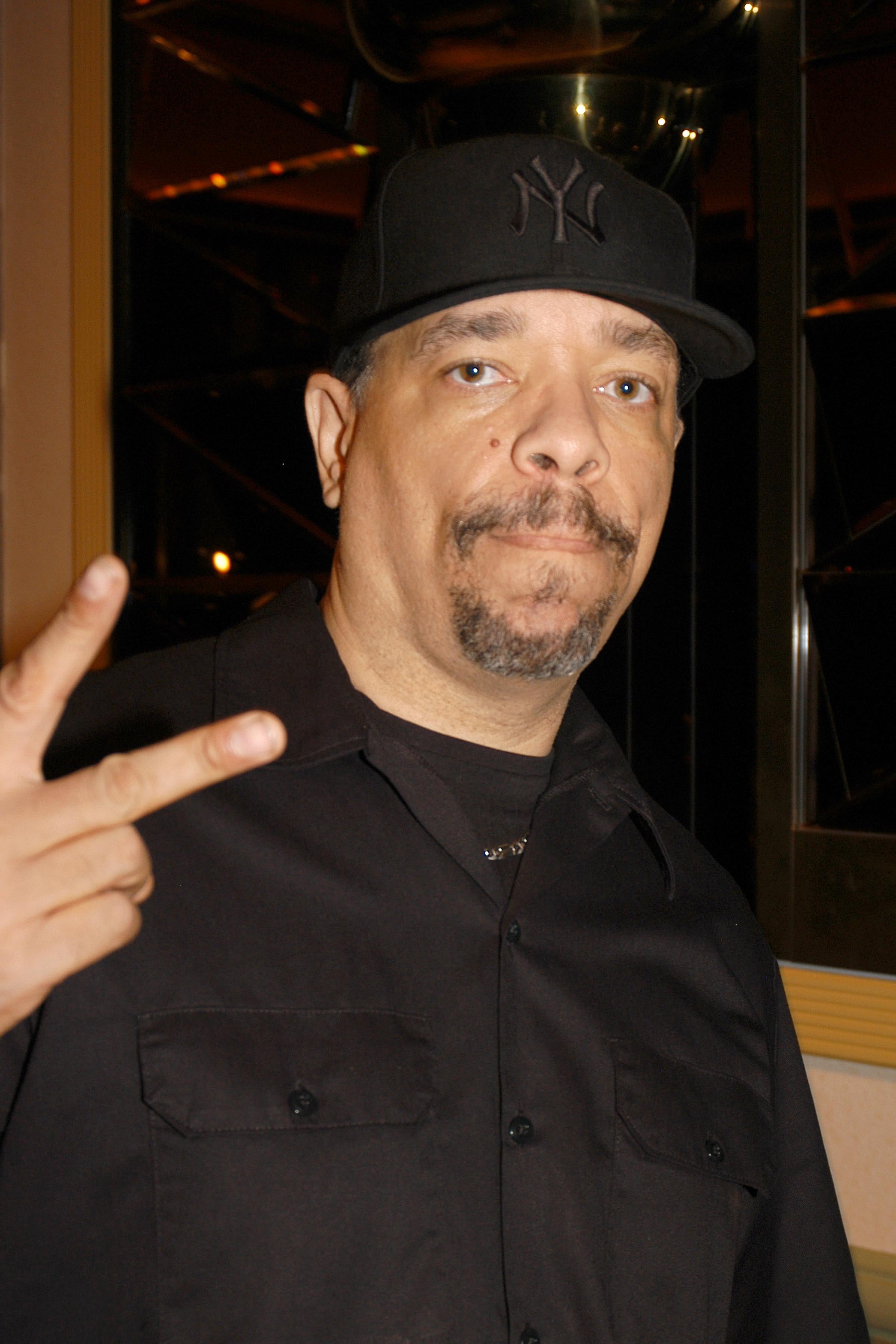 A person wearing a black cap and black shirt gestures with two fingers raised