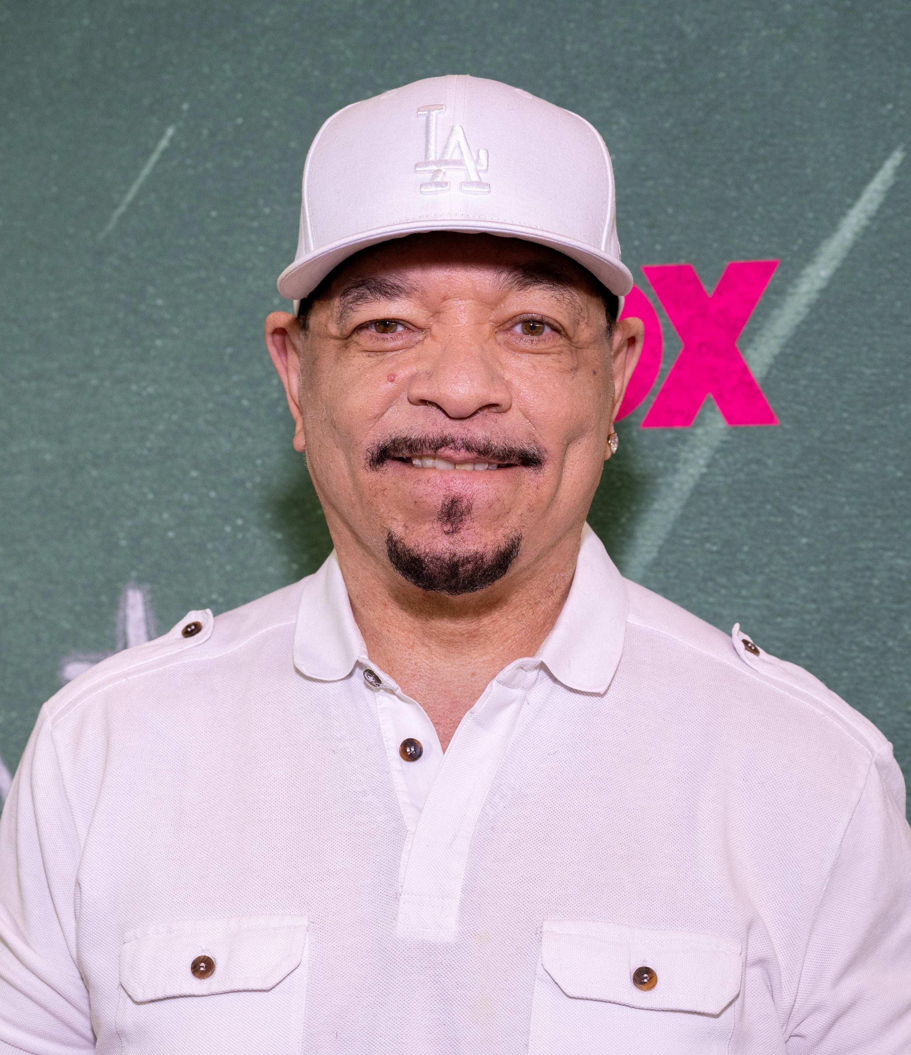 A person wearing a baseball cap and white shirt smiling at an event
