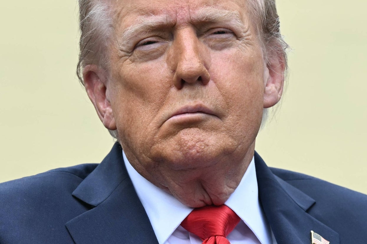 A person in a suit and red tie appears serious, looking slightly upward