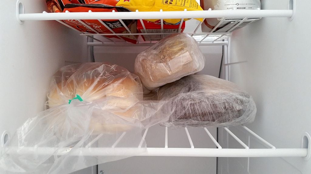 Frozen bread and pastries wrapped in plastic bags on a freezer shelf
