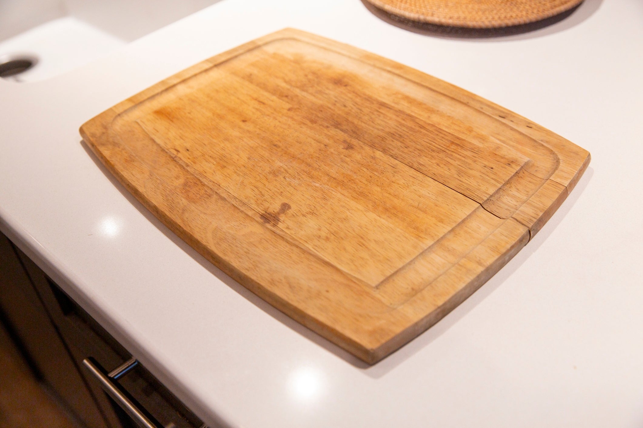 A wooden cutting board sits on a kitchen counter, ready for food preparation