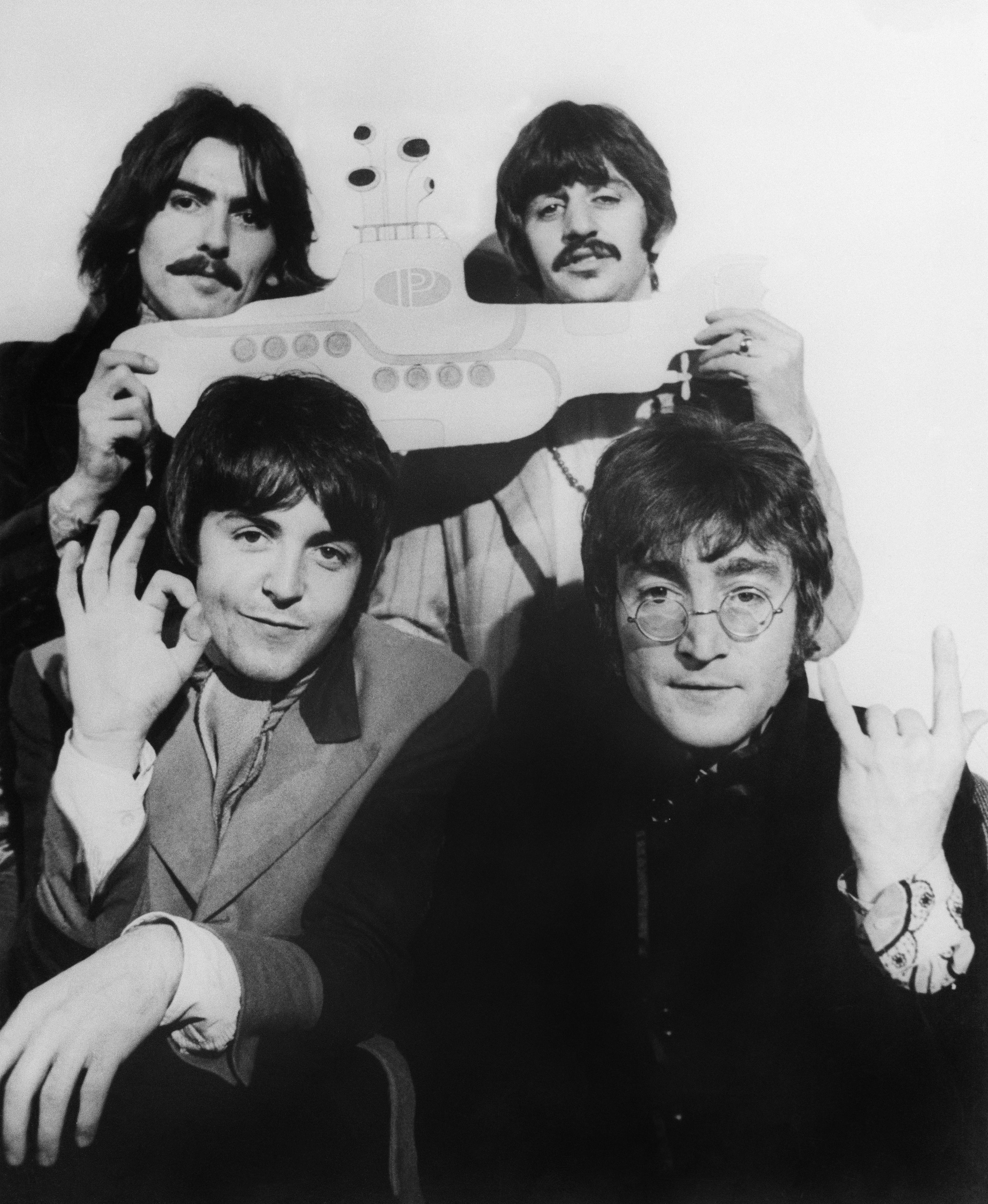 Four men smiling and posing with a submarine cutout