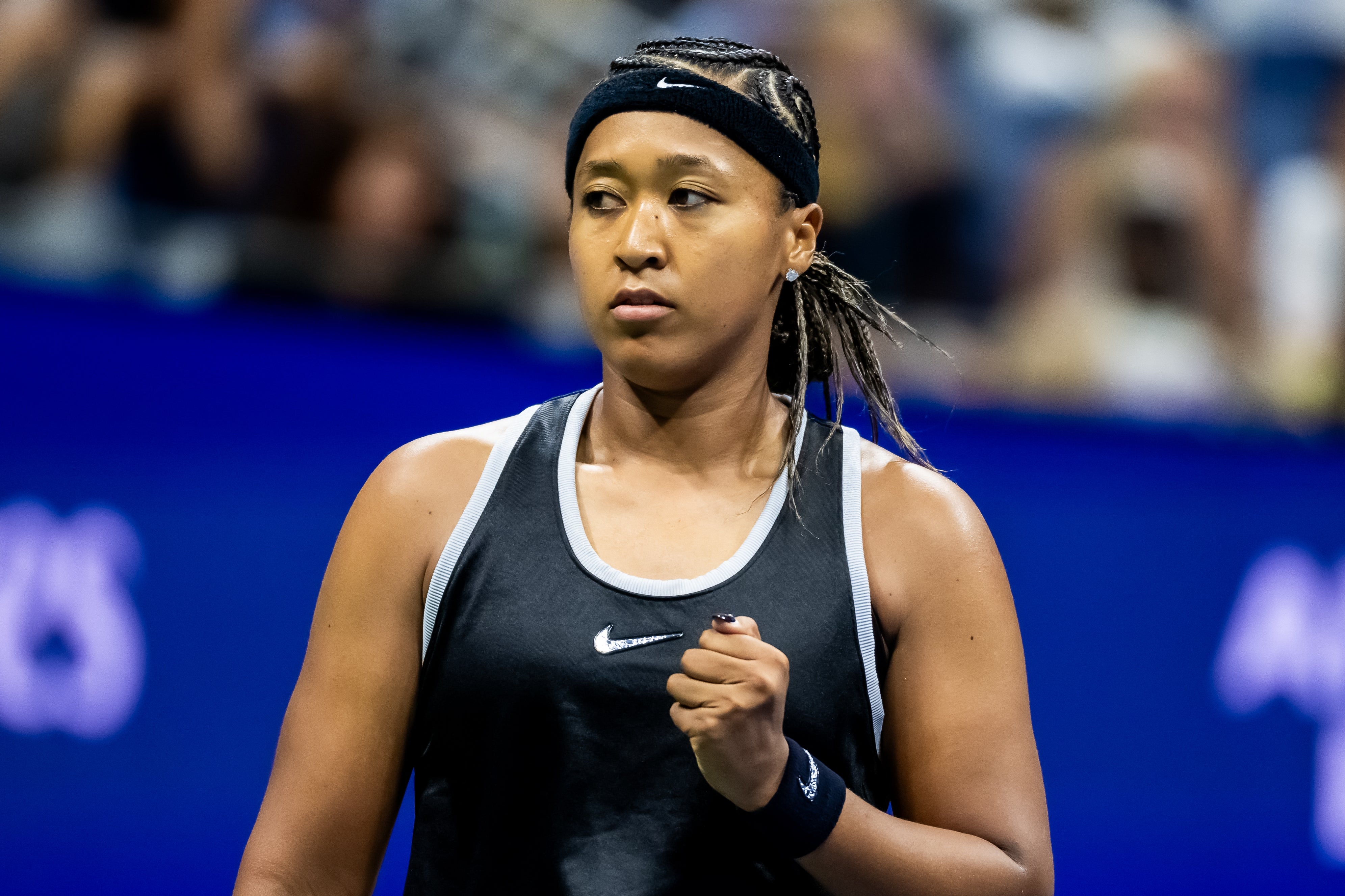 Tennis player on court, wearing athletic gear and a headband, appears focused and determined