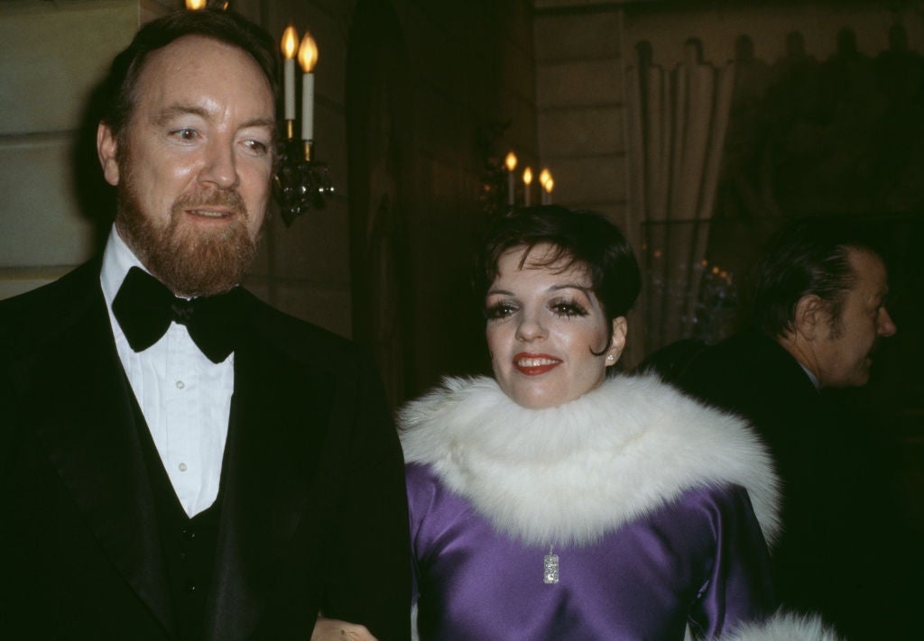 Man in tuxedo and woman in elegant dress with fur collar at an event