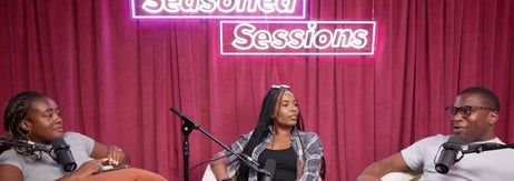 Three people sit in a podcast studio setting with microphones, beneath a neon sign reading "Seasoned Sessions"