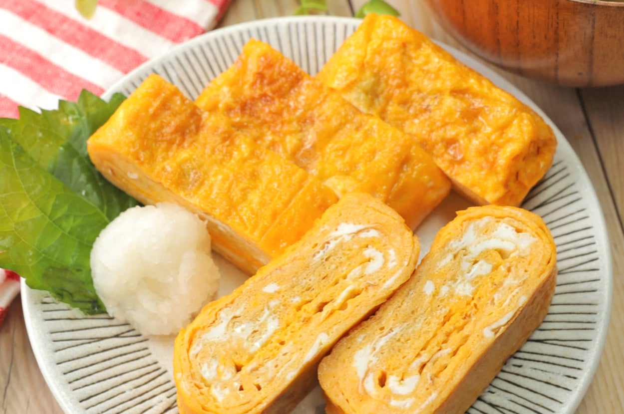 和食の皿に出汁巻き卵が3切れ、葉の付いた大根おろし、味噌汁が添えられている。