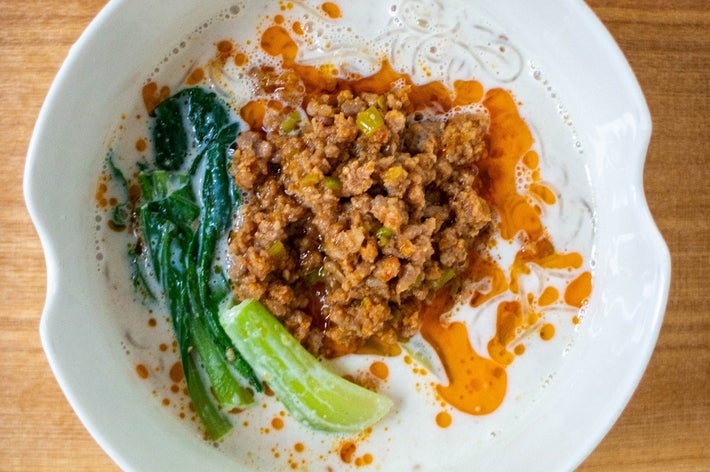 白い皿に担々麺が盛り付けられている。肉みそ、チンゲン菜、ラー油がかかっている。