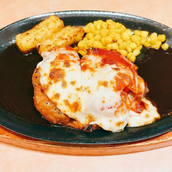 サイゼリヤ「柔らかチキンのチーズ焼き」鉄板に乗ったチキンのチーズ焼き、コーンとポテト付き。