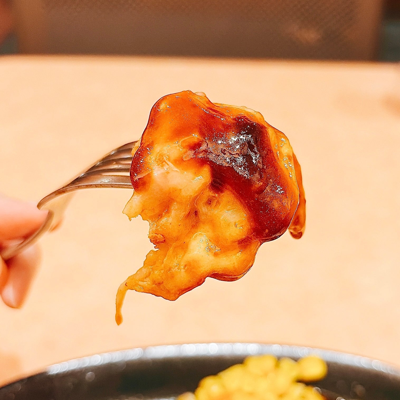 サイゼリヤ「柔らかチキンのチーズ焼き」フォークに刺さった一口サイズのチキン料理。