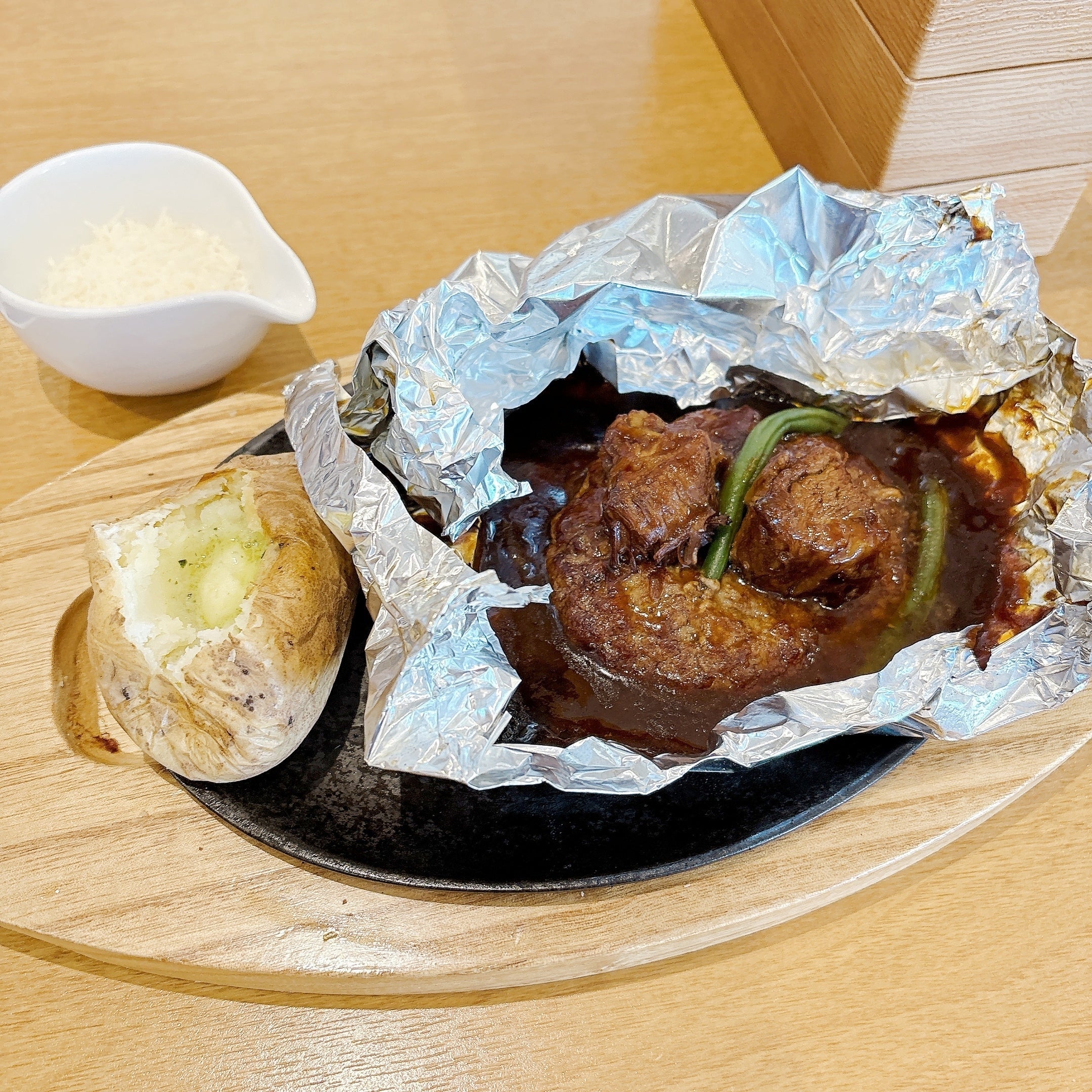 ココス「山盛りチーズの濃厚ビーフシチュー包み焼きハンバーグ145g」ホイルに包まれたハンバーグステーキ、焼きじゃがいも、チーズ入り。