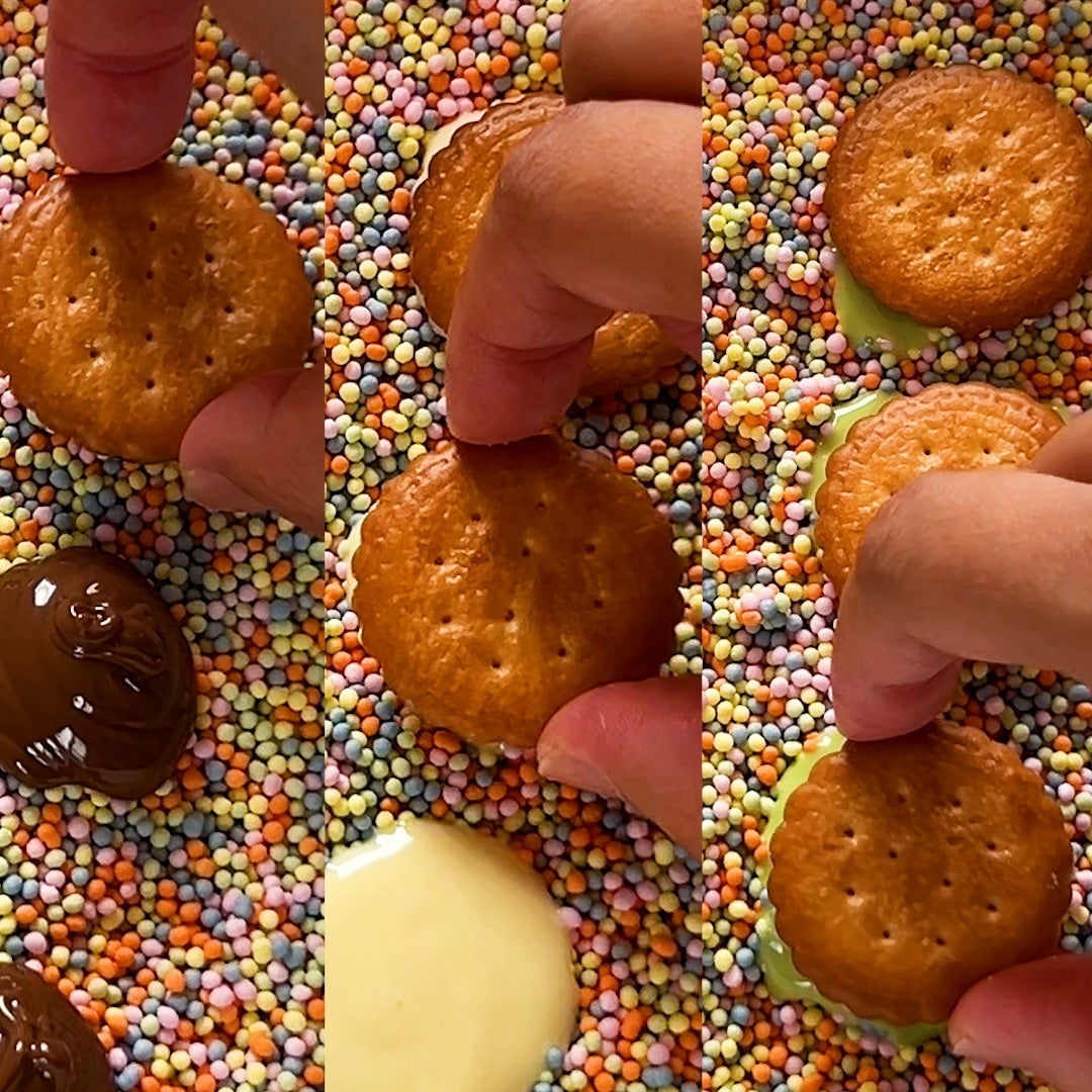 クラッカーをチョコレートにディップしてから、カラフルなスプリンクルにまぶしている様子。
