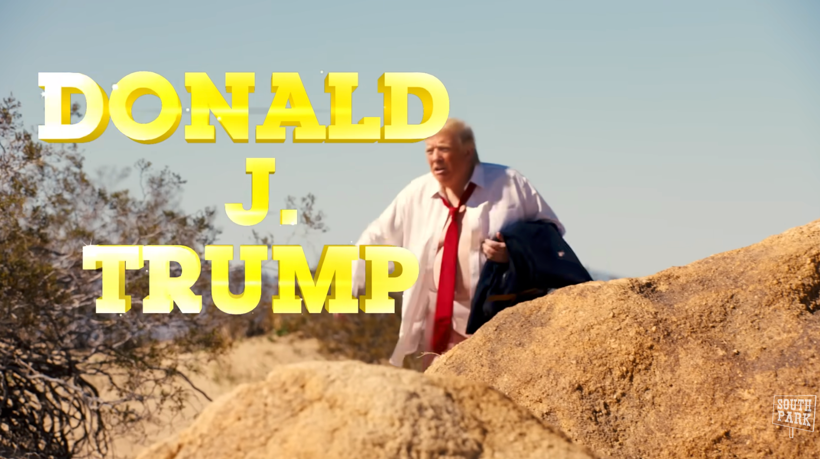 En mann i dress holder en jakke, stående på steinete terreng. Stor tekst lyder "Donald J. Trump."
