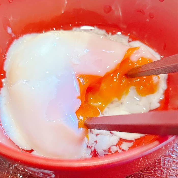 なか卯の「まぜのっけごはん朝食」温たまを箸で割っている様子。