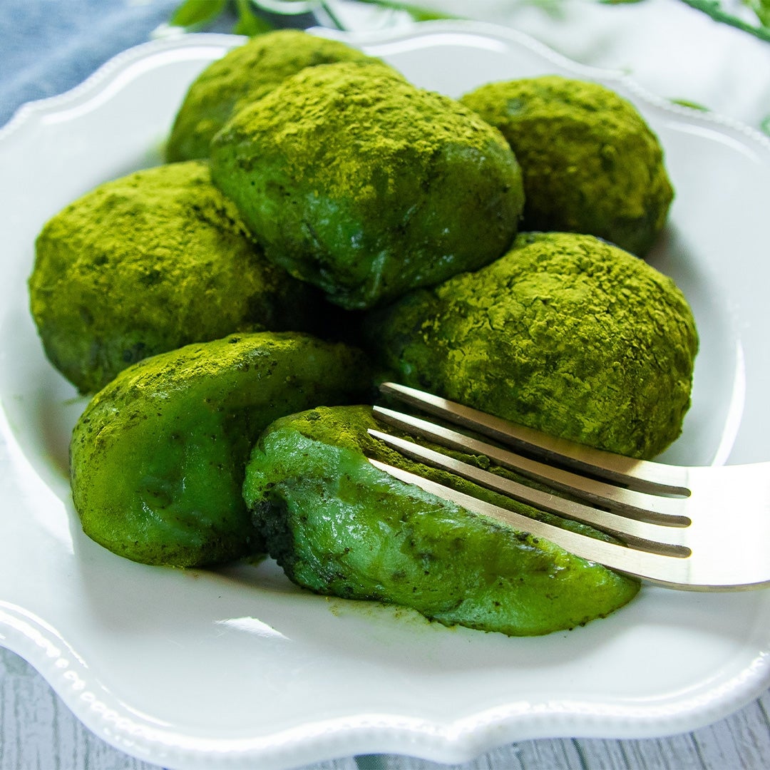 フォークで抹茶パウダーがかかった緑色の餅をつぶしている。