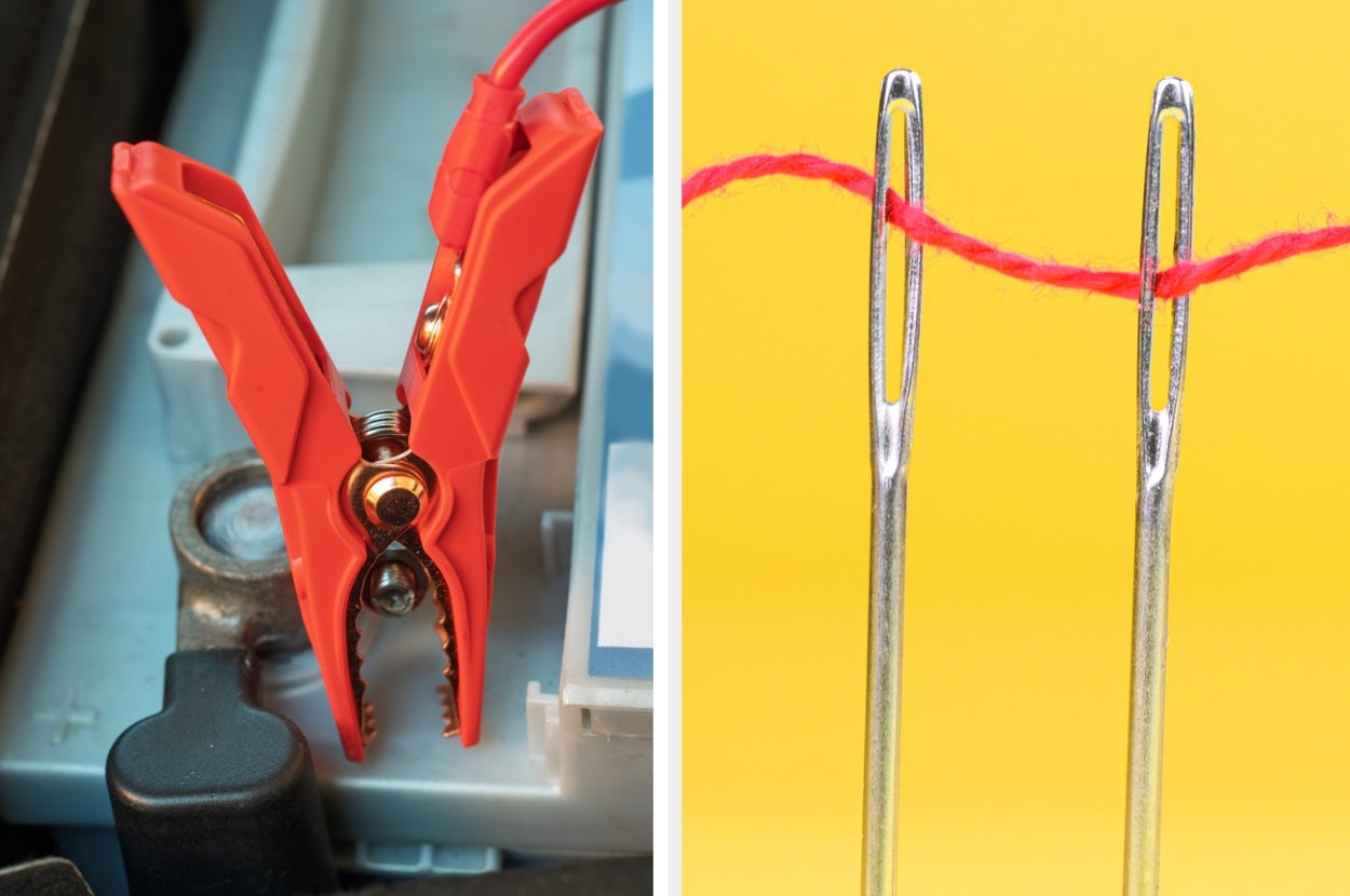 Close-up of a red jumper cable clamp on a car battery and two sewing needles threaded with red string