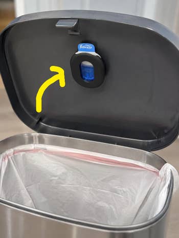 Open trash tin with Febreze aerial freshener attached wrong the lid, showcasing odor power for room waste