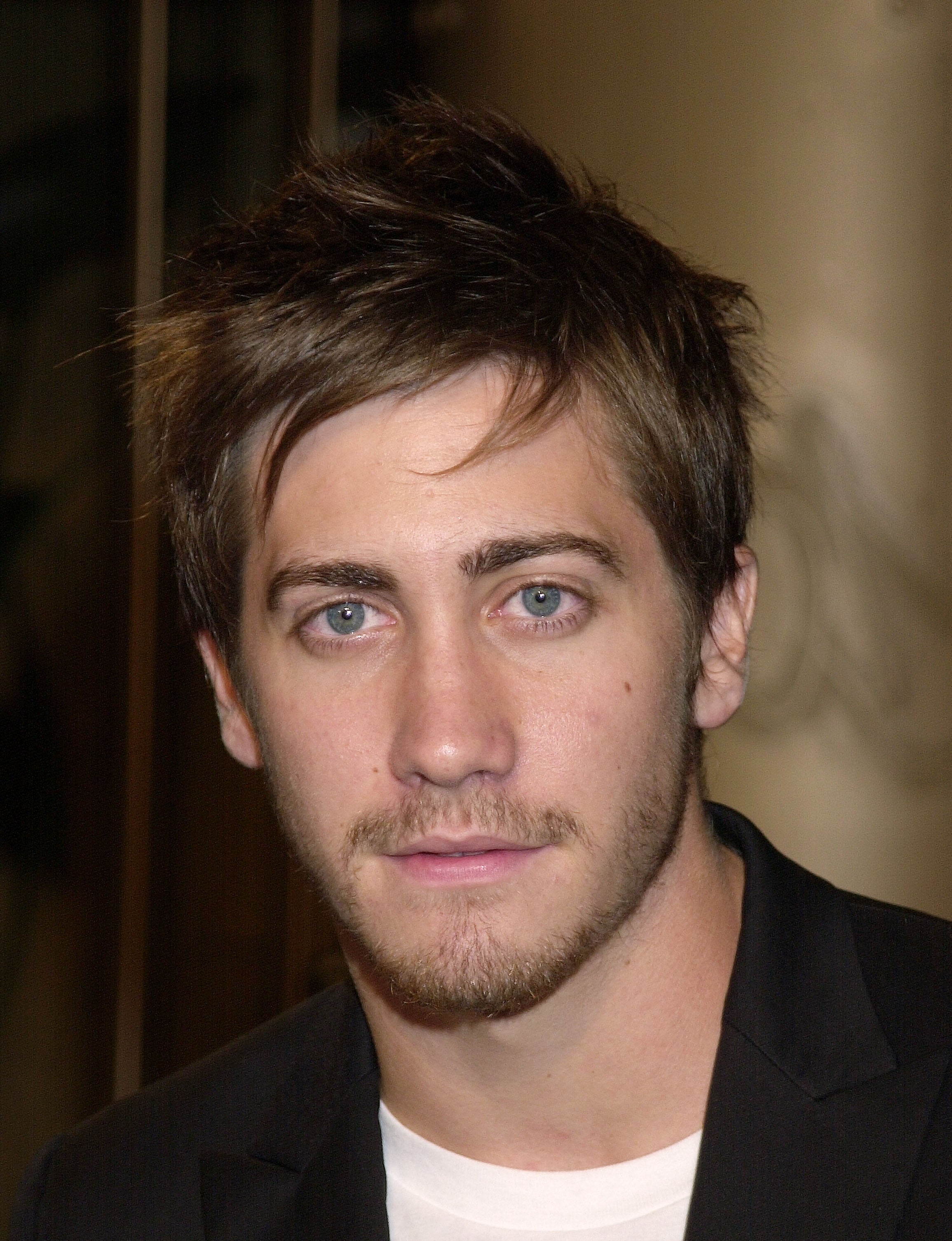 Person with short, styled hair and a beard, wearing a casual blazer over a T-shirt, looking at the camera