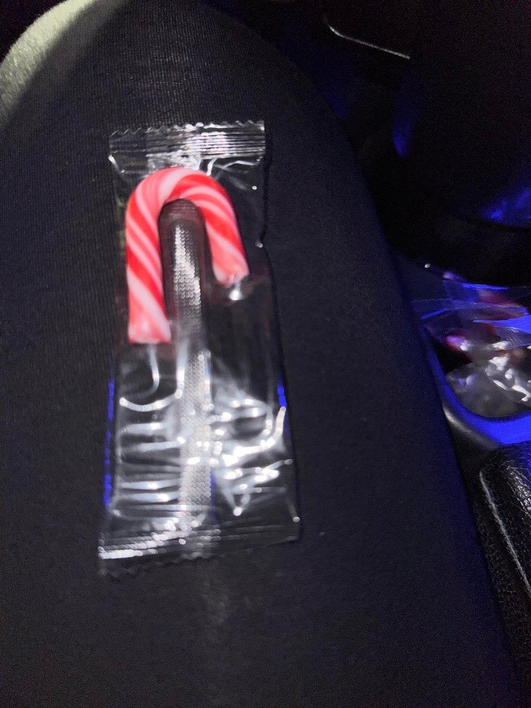 Unwrapped candy cane resting connected  someone's thigh  successful  a car