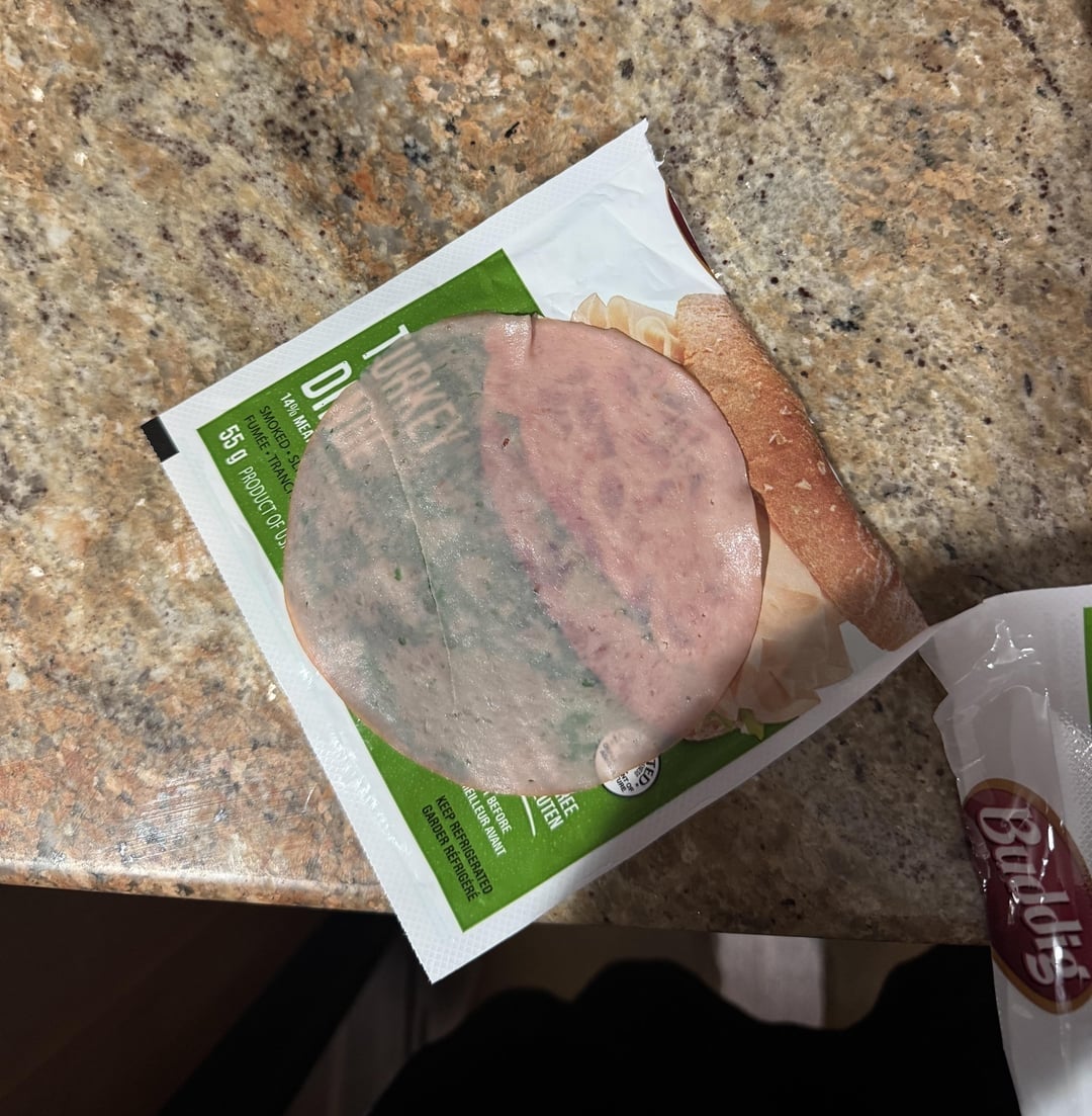 A portion    of turkey luncheon  nutrient   connected  a room  counter, placed backmost  successful  its partially opened packaging