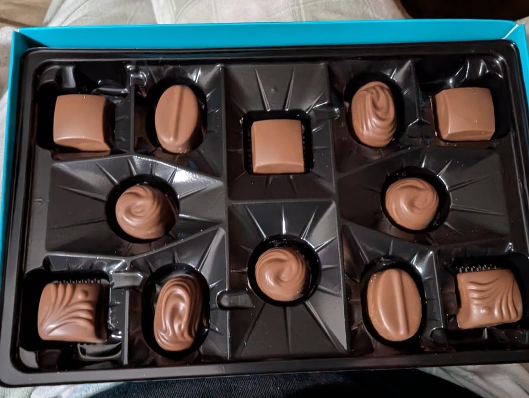 A container  of assorted chocolates with antithetic  shapes and textures, neatly arranged successful  a tray