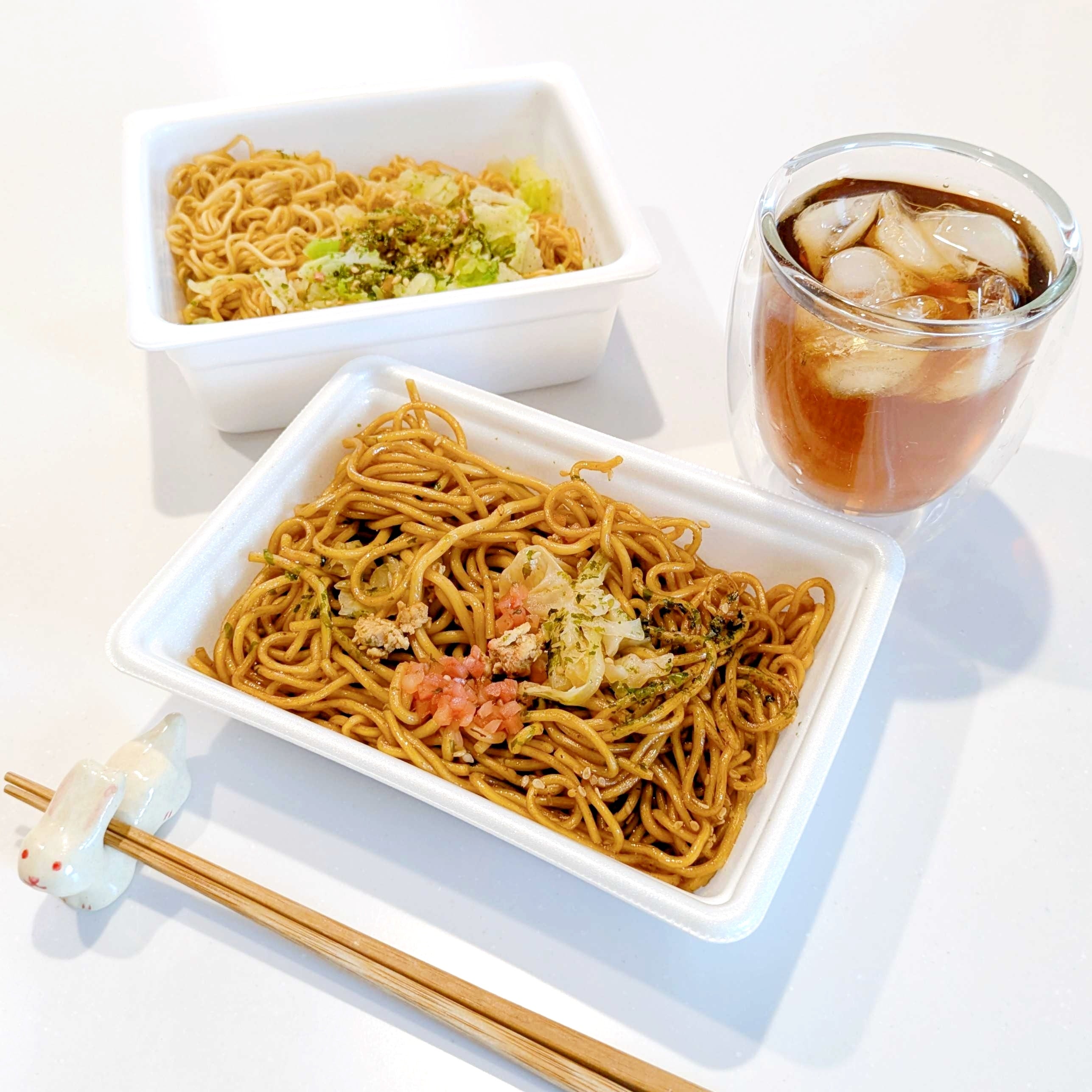 ファミリーマート「生ペヤングソースやきそば」焼きそば2つとアイスティー、箸がテーブルに置かれた食事シーン。