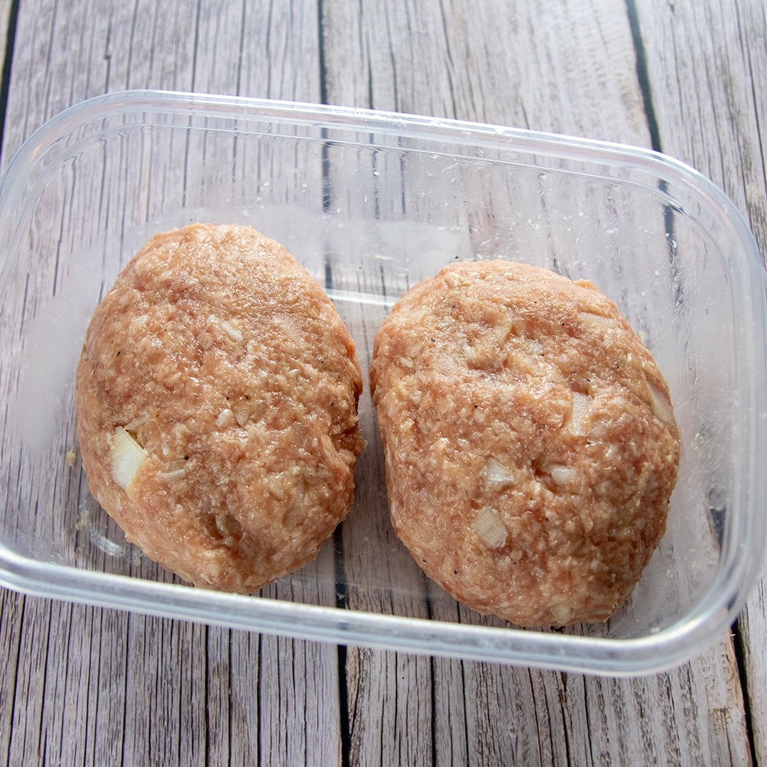 透明な容器に入った2つの生のハンバーグパティ。