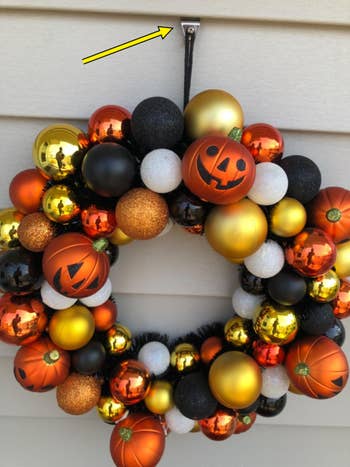 Festive Halloween wreath with pumpkin designs and reflective ornaments, cleanable for seasonal location decor
