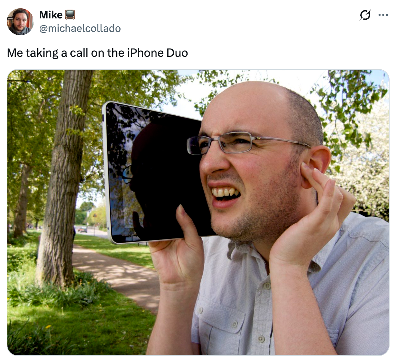 Person som på humoristisk vis later til å ta en samtale med et stort nettbrett holdt mot øret, og imiterer å bruke en gigantisk telefon i en park.
