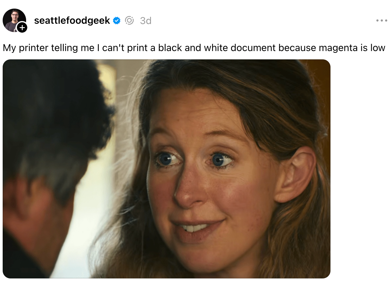 En person ser underholdt eller forvirret ut mens han snakker med noen utenfor kameraet; bildeteksten nevner humoristisk en skrivers magenta blekkproblem