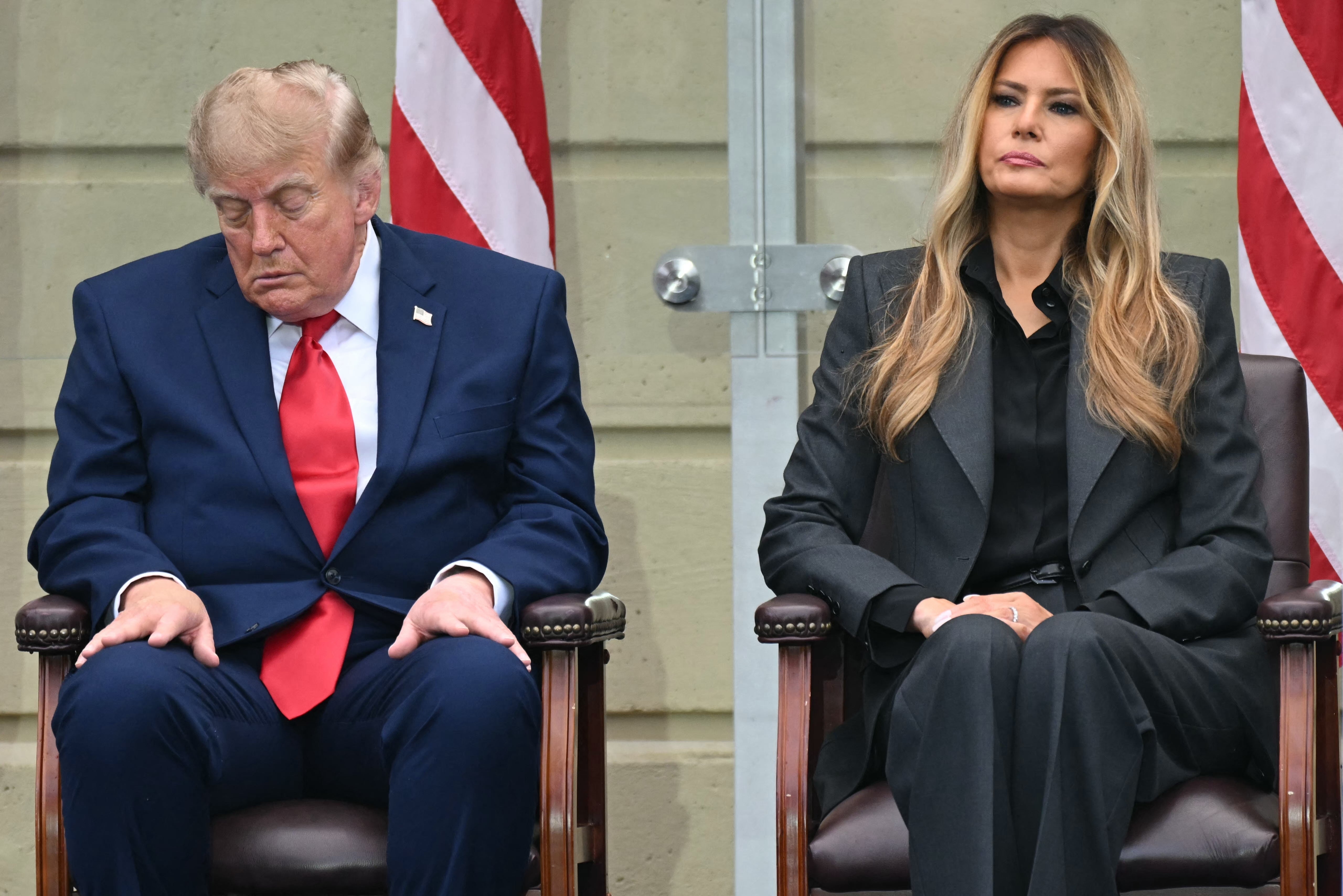 Donald Trump satt ved siden av Melania på et arrangement; han ser ned på skoene sine og øynene er nesten lukket