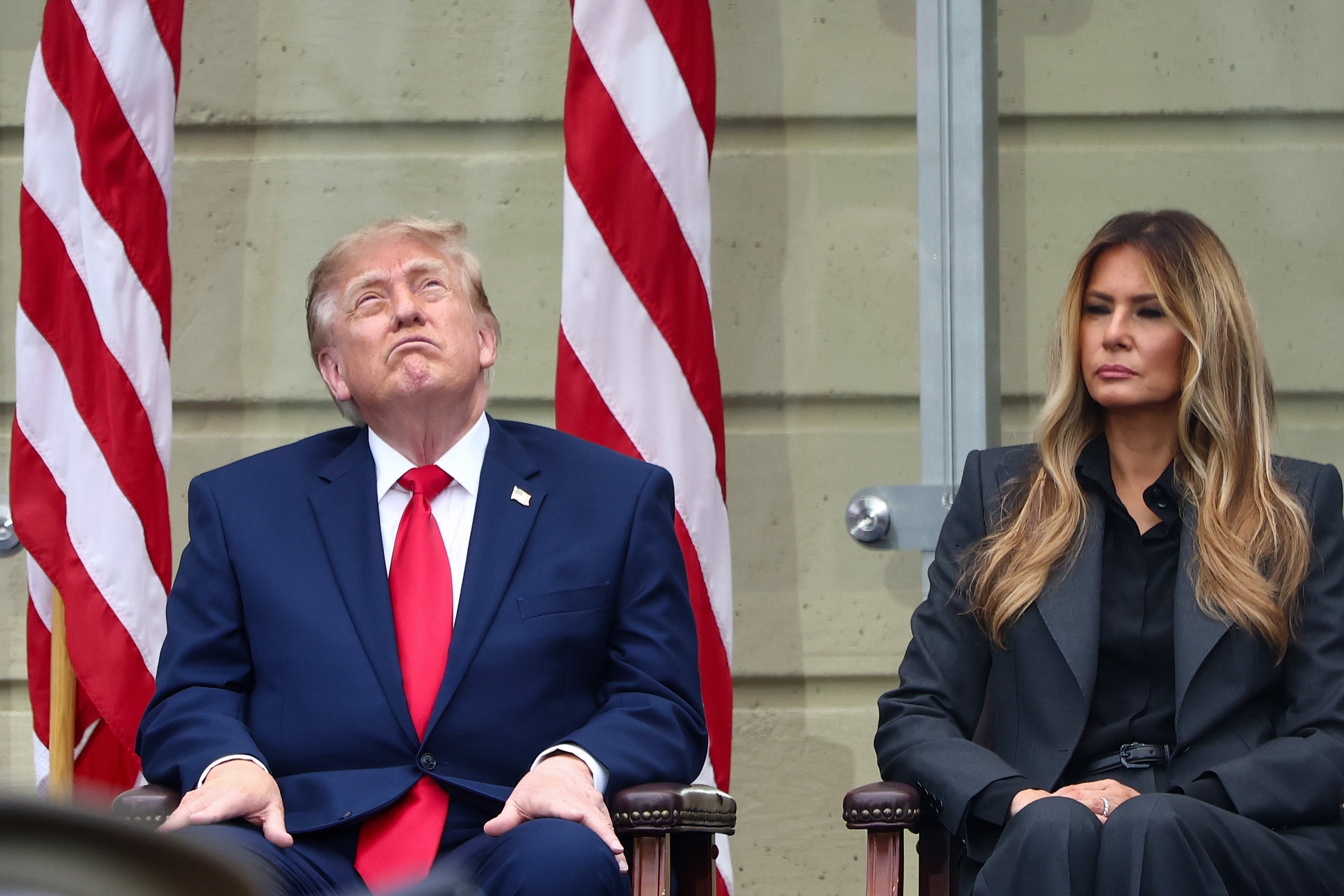 Donald Trump satt ved siden av Melania på et arrangement; han myser mot himmelen