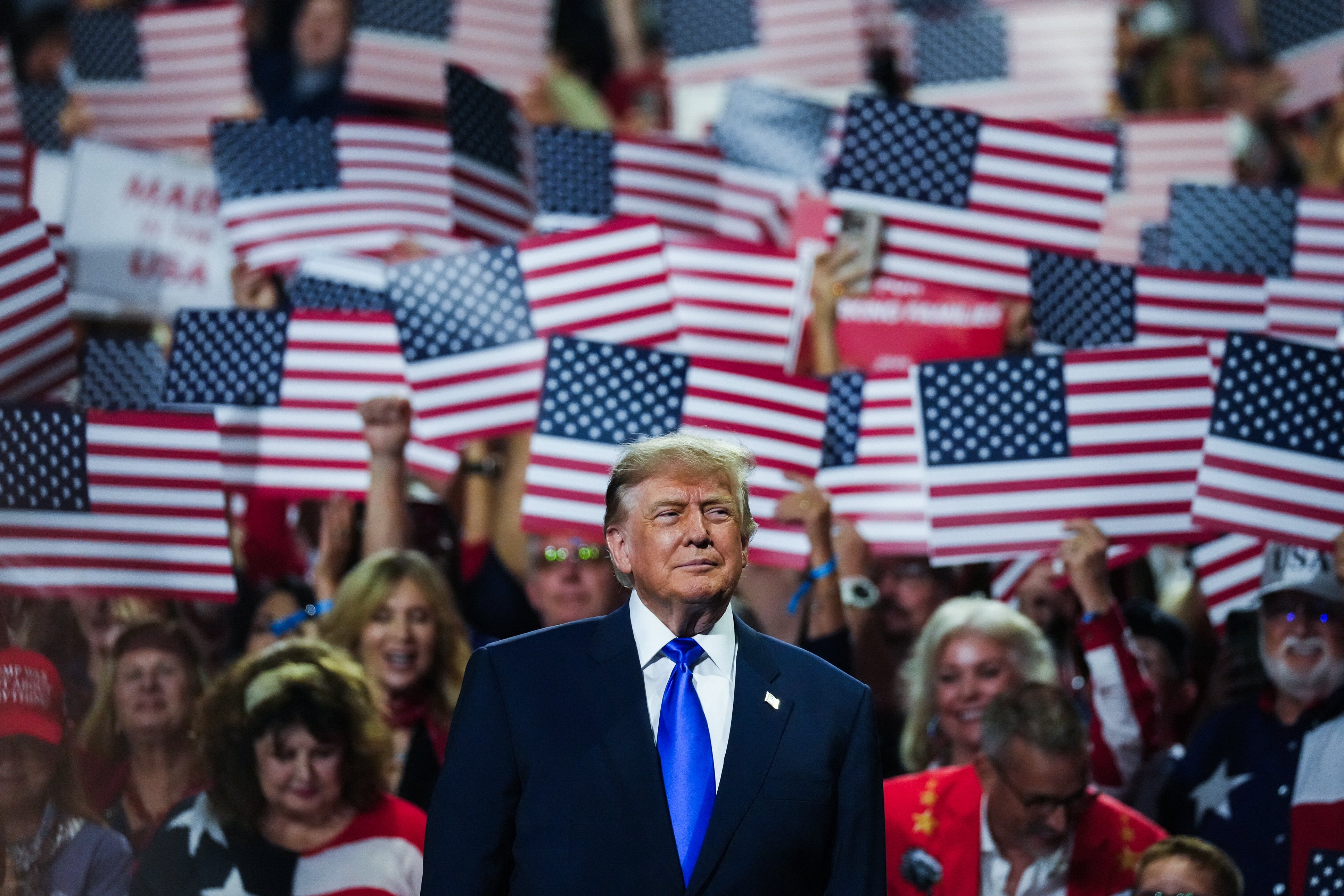 Person i dress på et rally med en folkemengde som holder amerikanske flagg i bakgrunnen