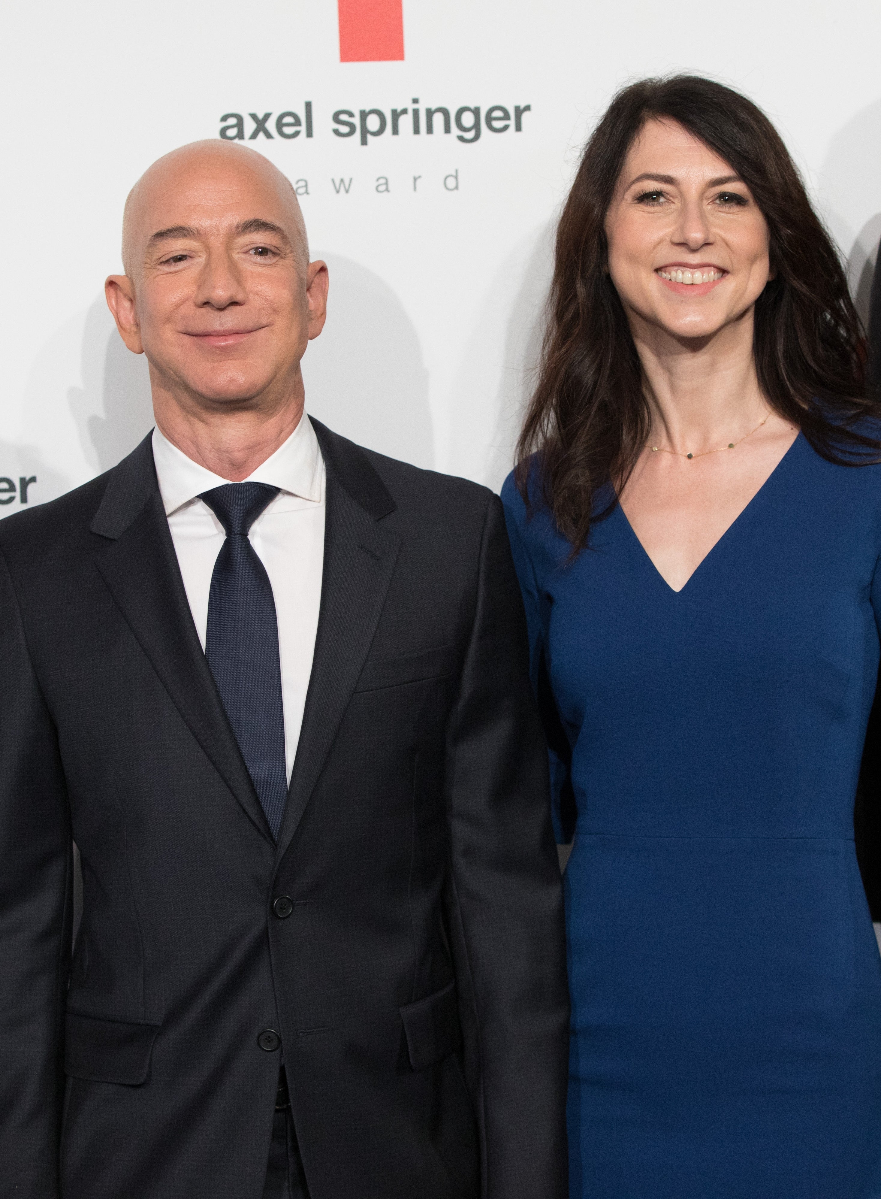 Jeff Bezos and MacKenzie Scott pose in formal attire at an Axel Springer Award event. Bezos wears a suit and tie, and Scott wears a navy blue dress