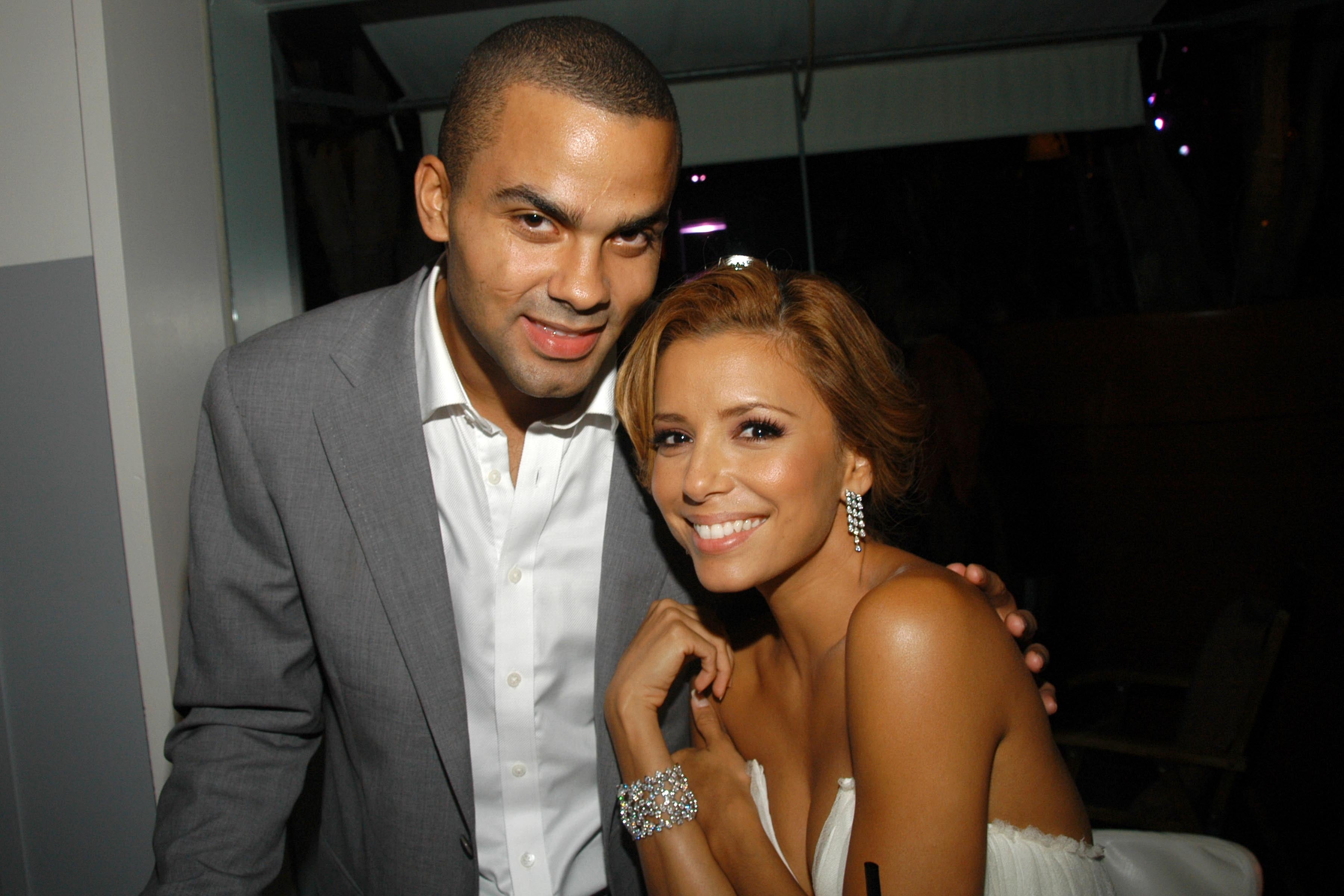 A smiling woman in a strapless dress poses with a man in a suit at an event
