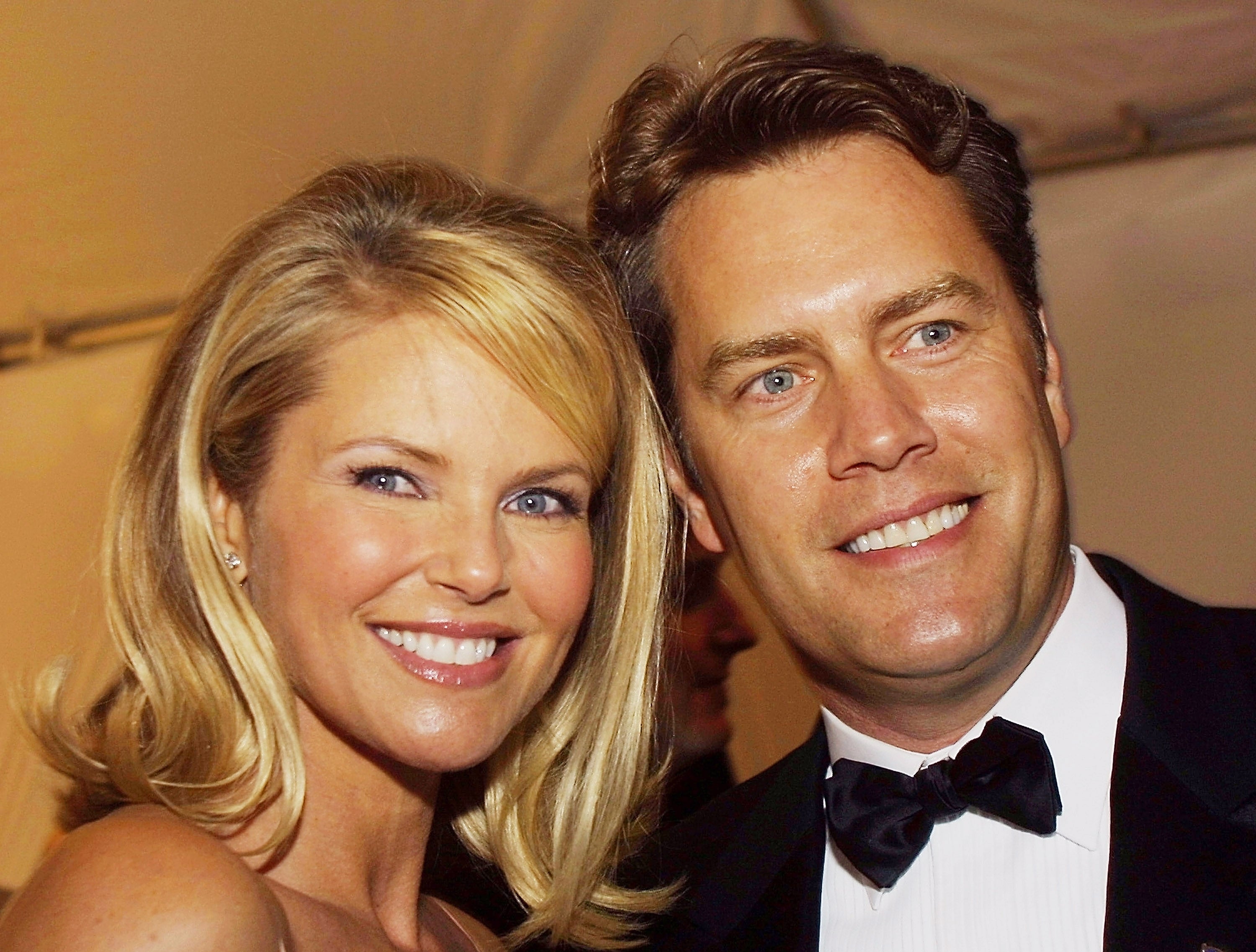 I don't know who these individuals are, but they're at an event; the woman wears an elegant gown and the man is in a suit and bow tie, both smiling