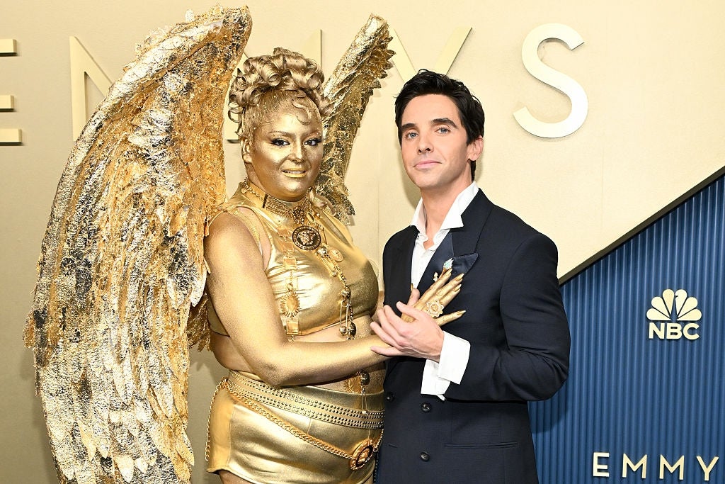 Meg in gold winged costume poses with Paul in a formal suit