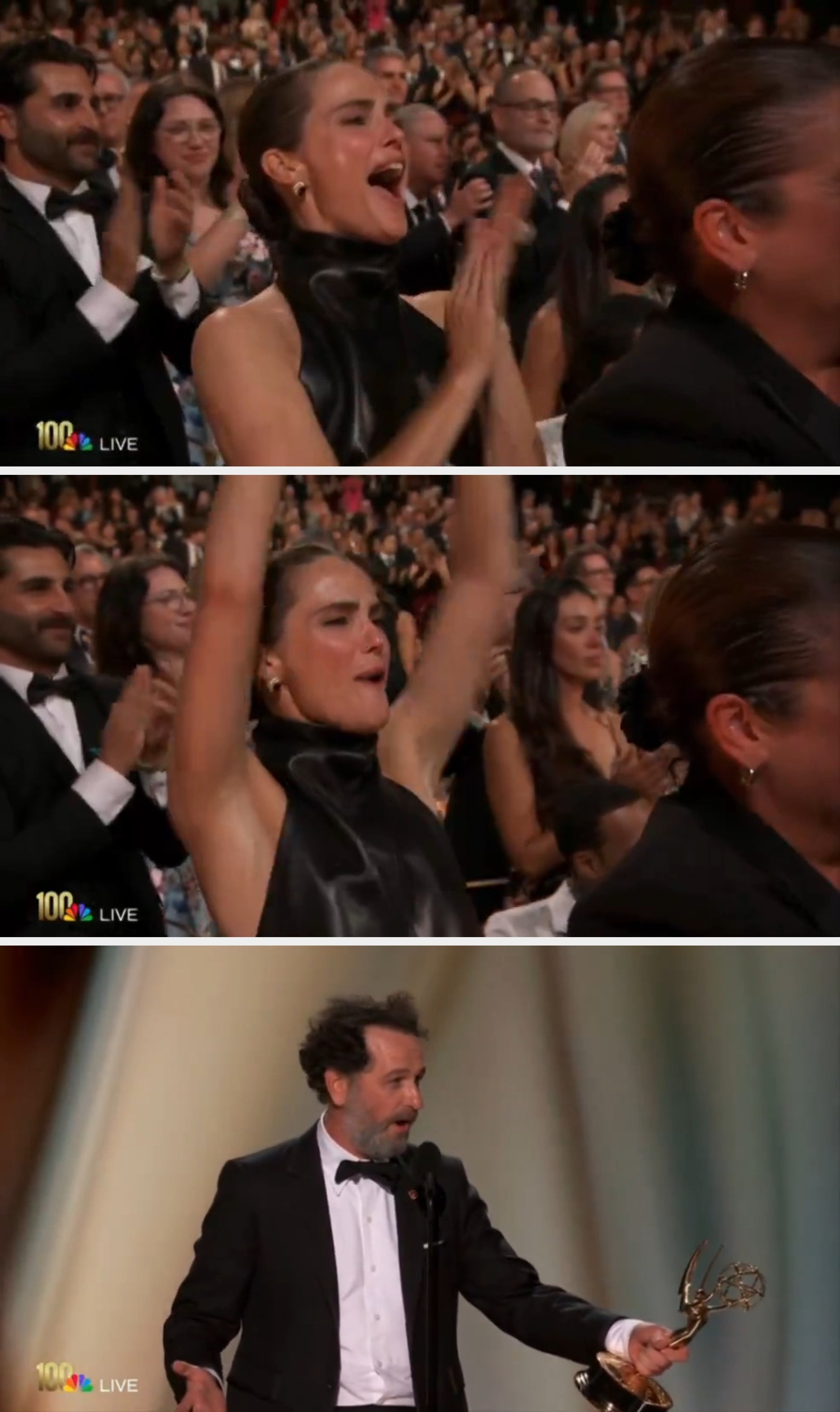A person in elegant attire claps and cheers enthusiastically at an award event, surrounded by a standing audience