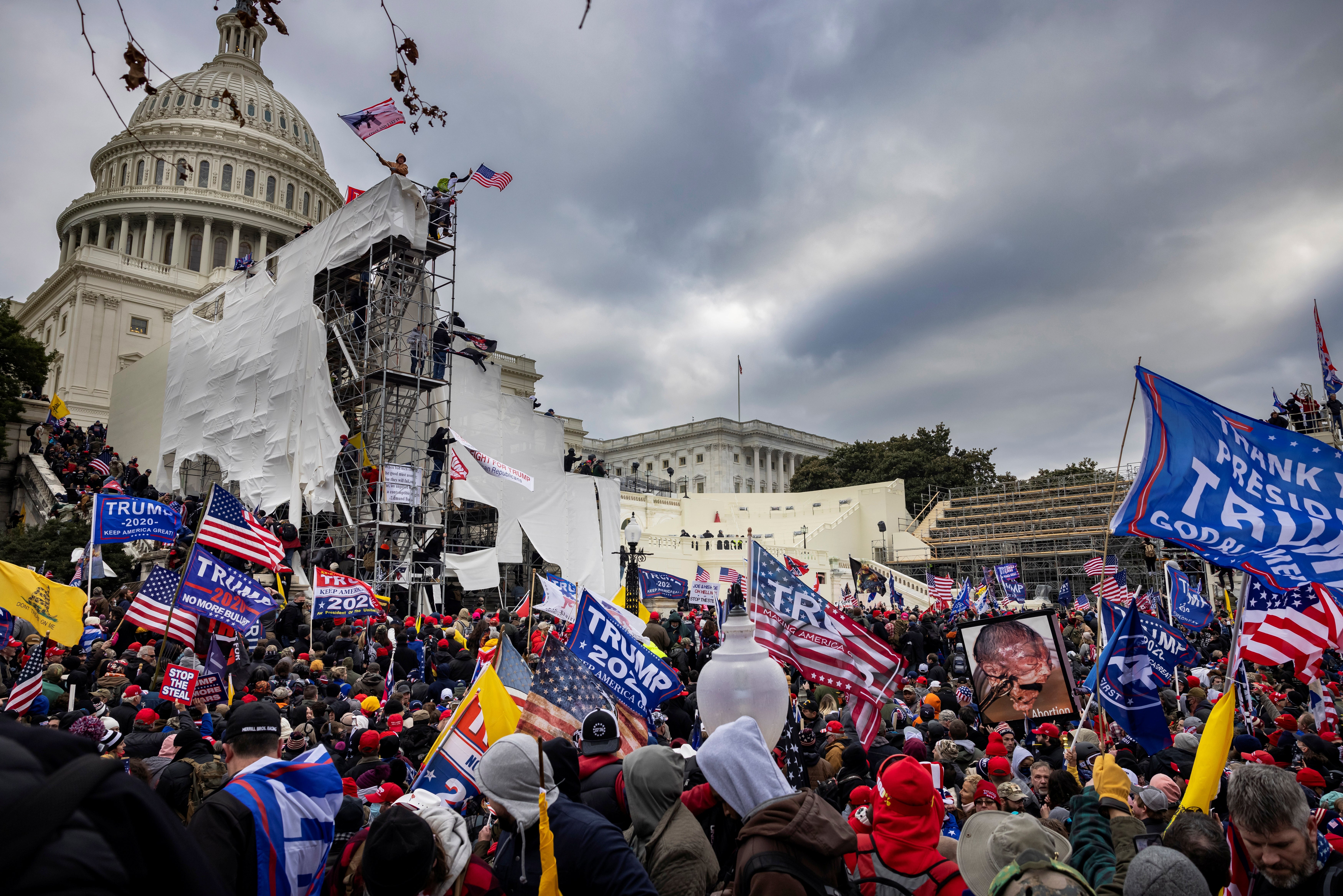 Folkemengde med flagg utenfor US Capitol under en protest. Stillaser og Capitol-kuppelen er synlige i bakgrunnen