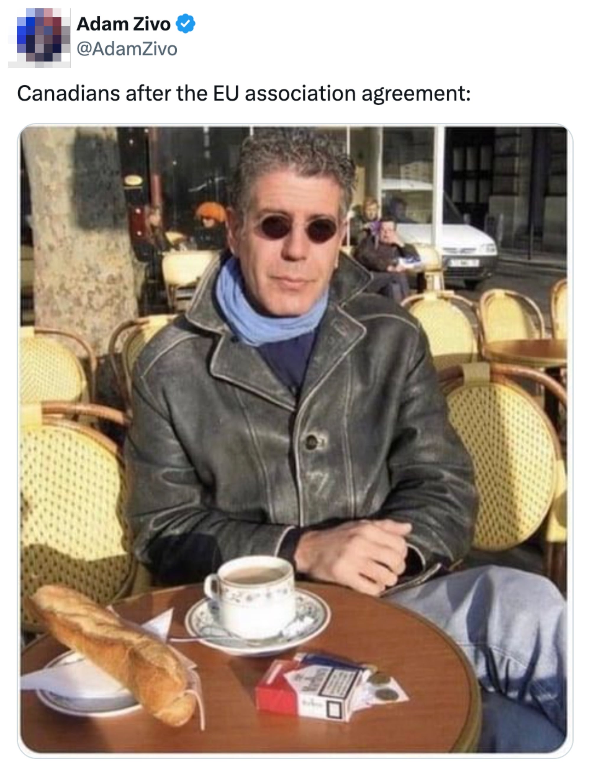 En person i en skinnjakke sitter ved et kafébord med en kopp kaffe, en baguette og en pakke sigaretter, og fanger en avslappet europeisk stemning