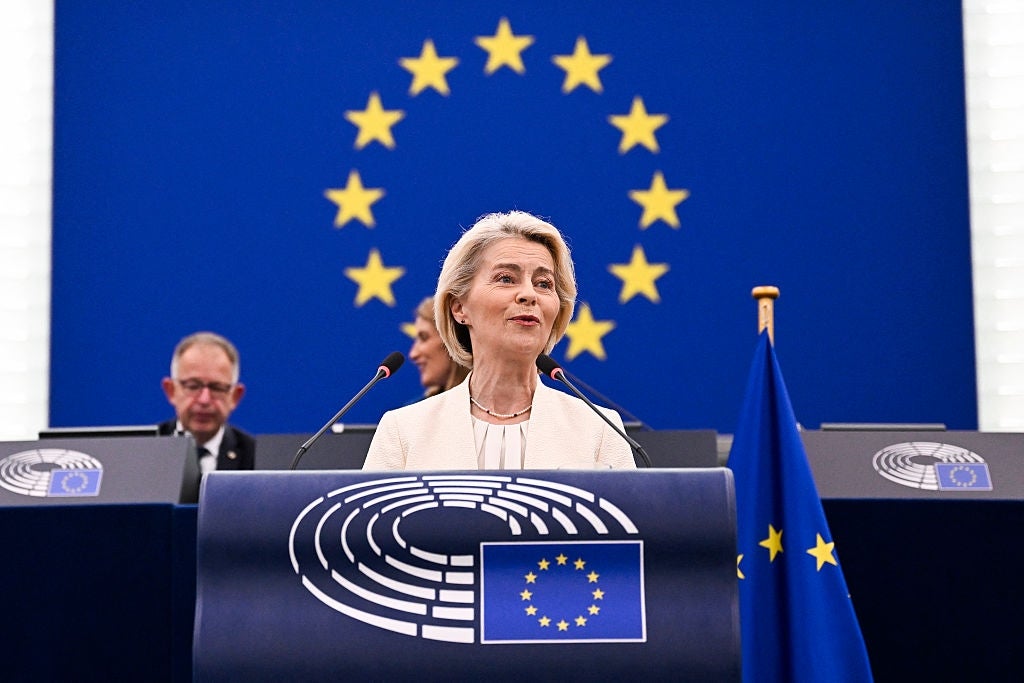 En person taler på et podium foran et EU-flagg i bakgrunnen og tjenestemenn, under en formell begivenhet
