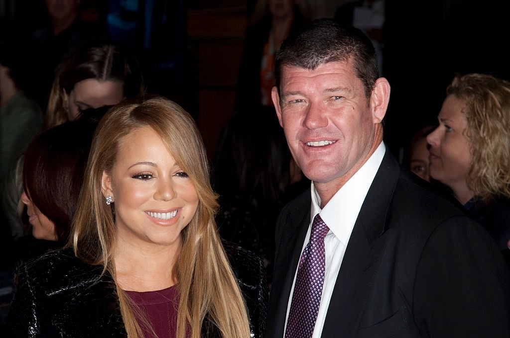 Two individuals at an event; the woman is wearing a stylish dress, and the man is in a suit, both smiling for the camera