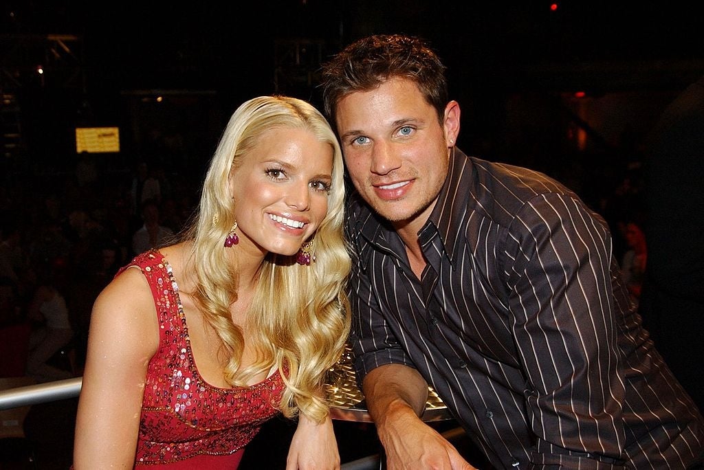 Two people smiling at an event. The woman wears a sequined dress, and the man wears a striped shirt