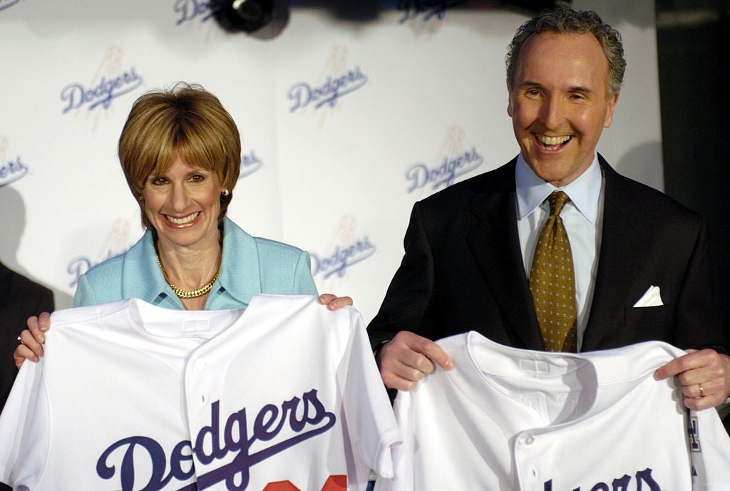 Two people smiling and holding Dodgers jerseys at a press event
