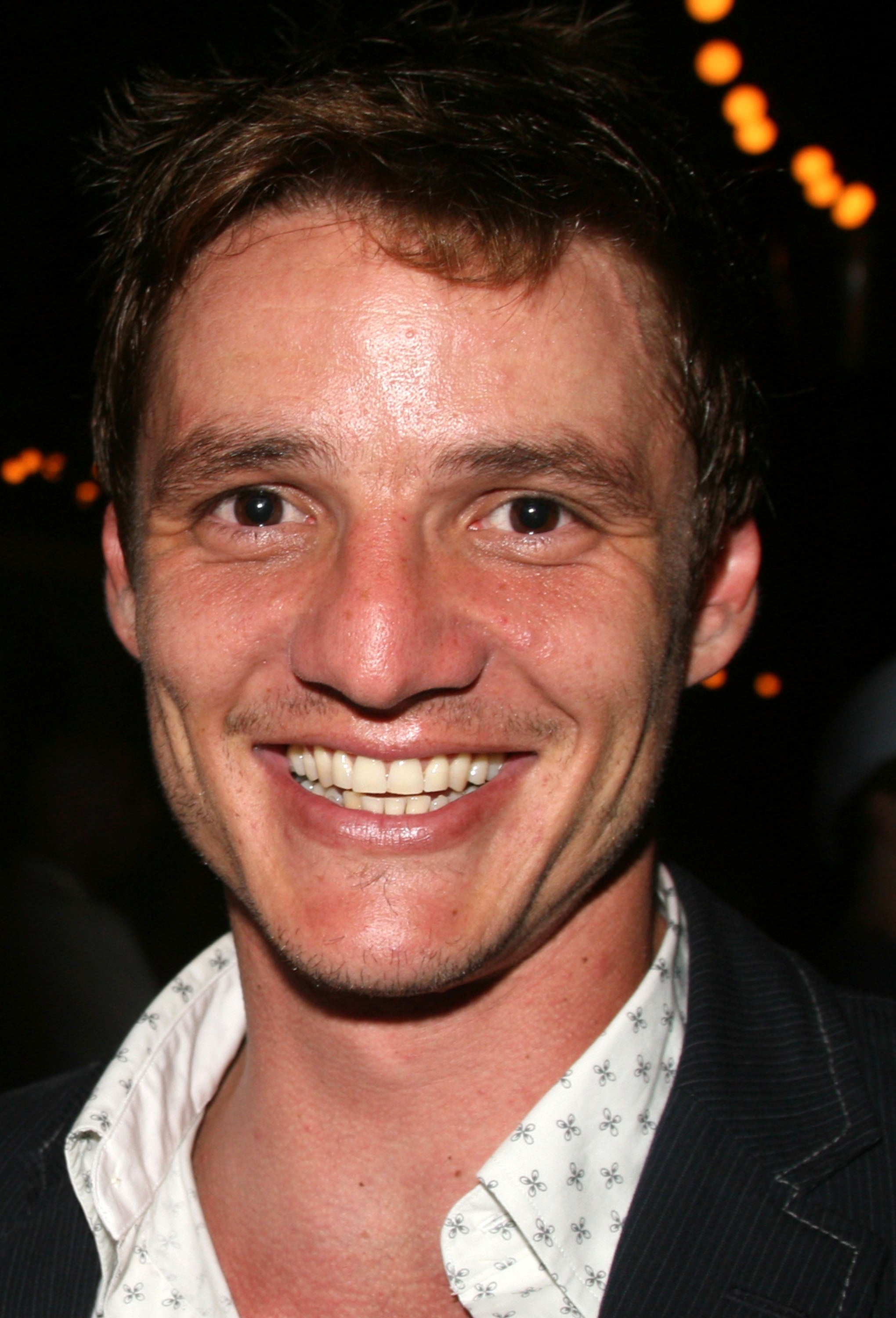 Smiling person wearing a patterned shirt and blazer at an event