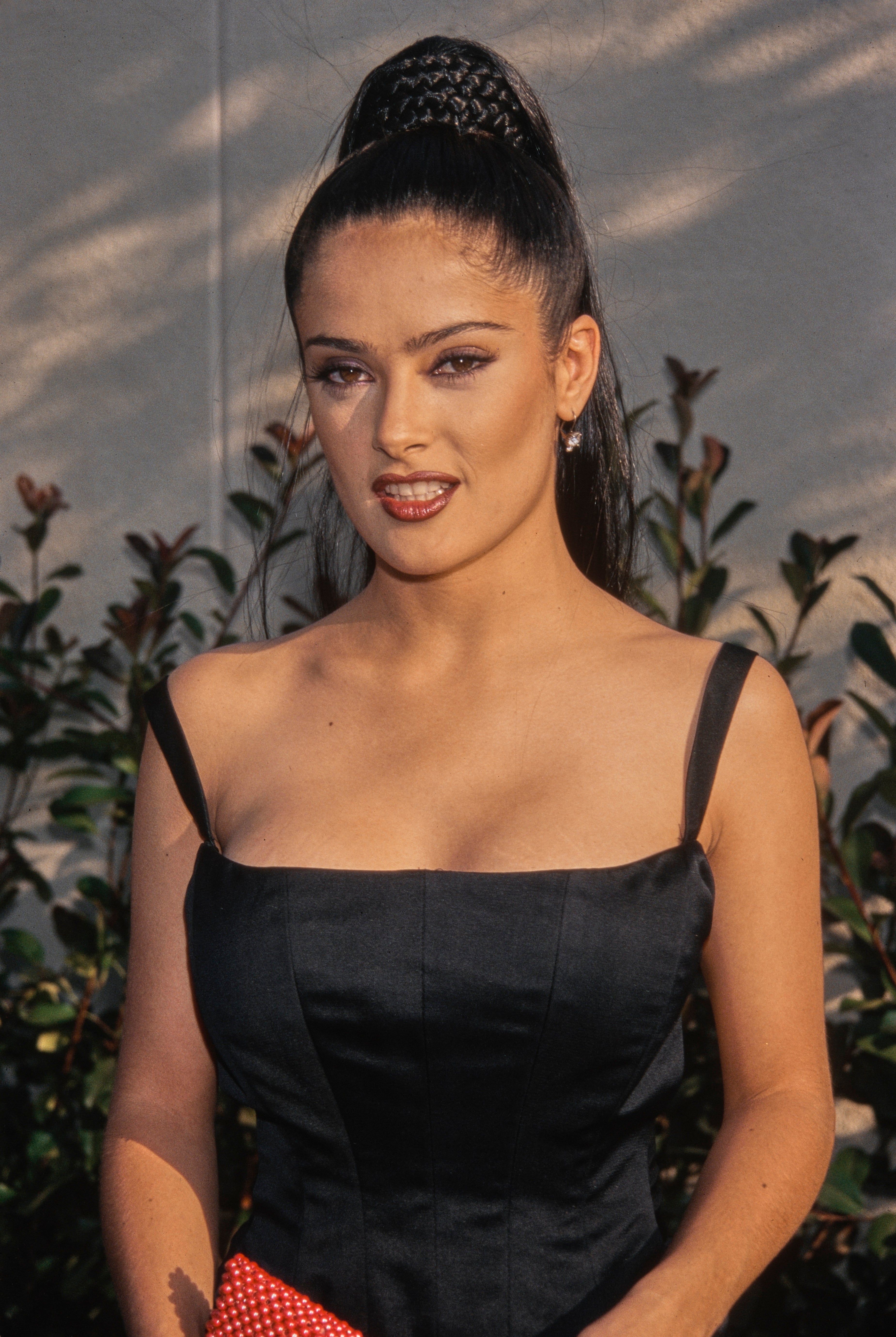 Person in a fitted, sleeveless dress with braided hairstyle, standing outdoors