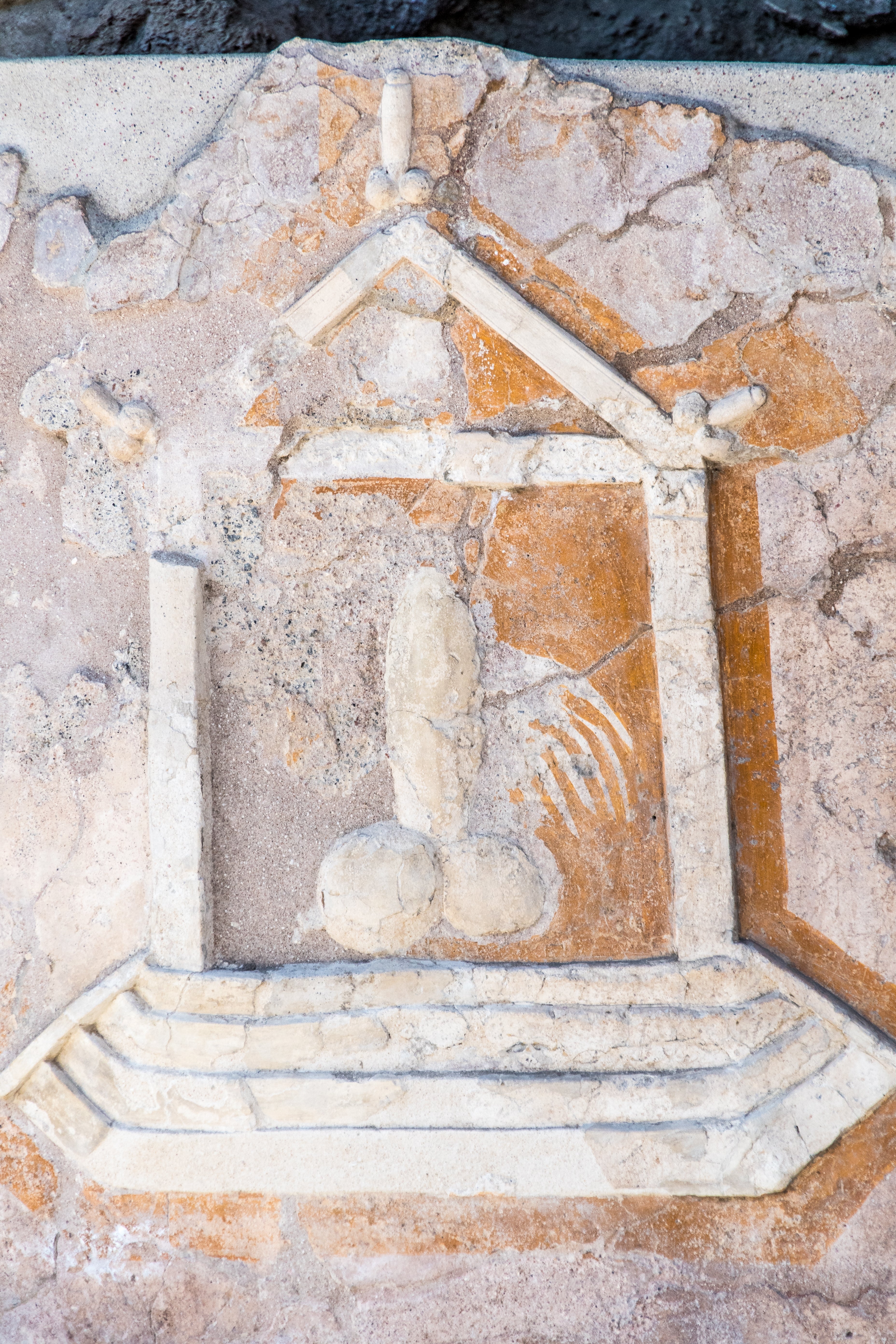 Ancient stone carving depicting a figure and architectural elements, worn and eroded over time