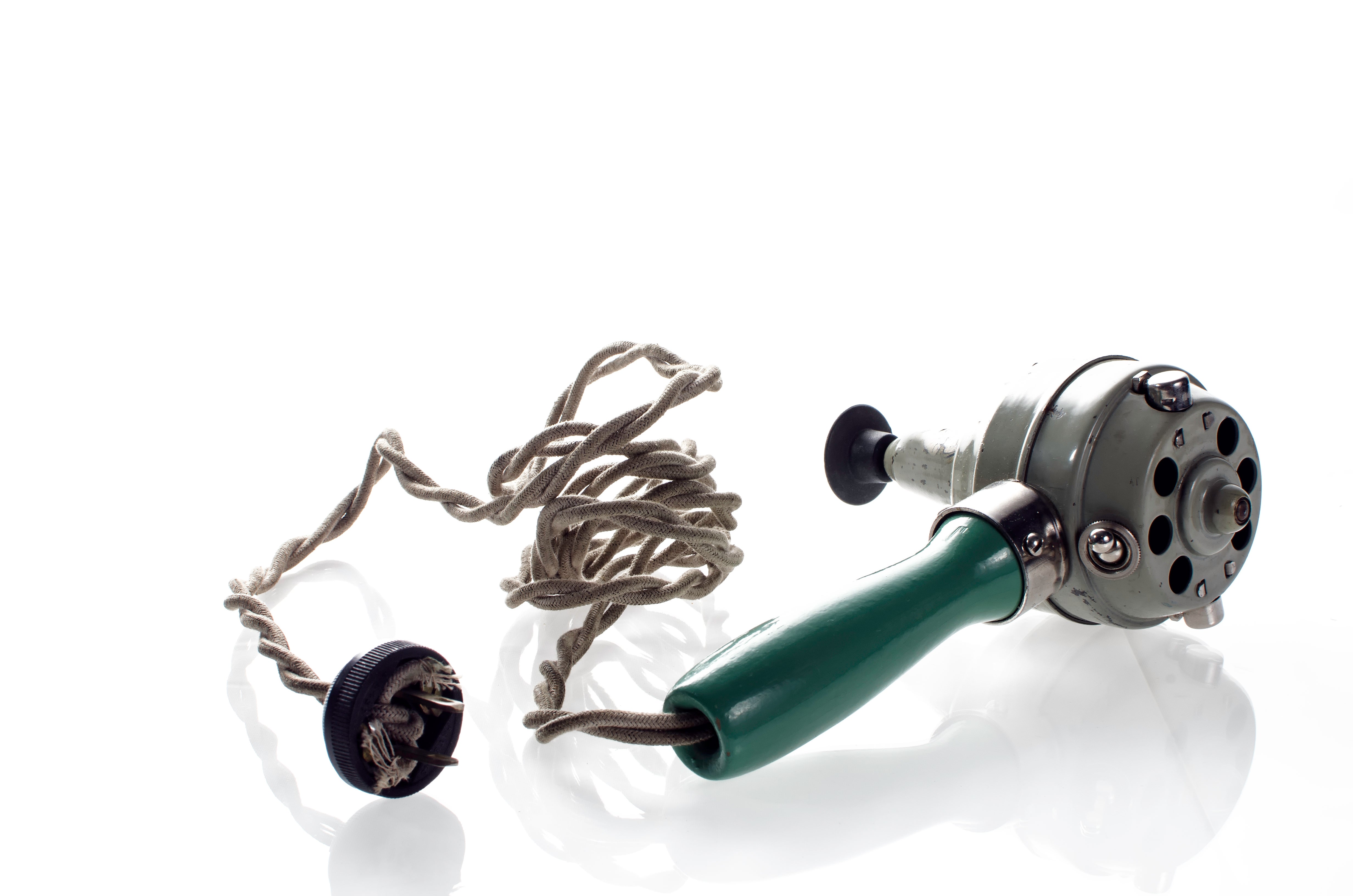 Vintage handheld massager with a frayed cord and a green handle on a white background