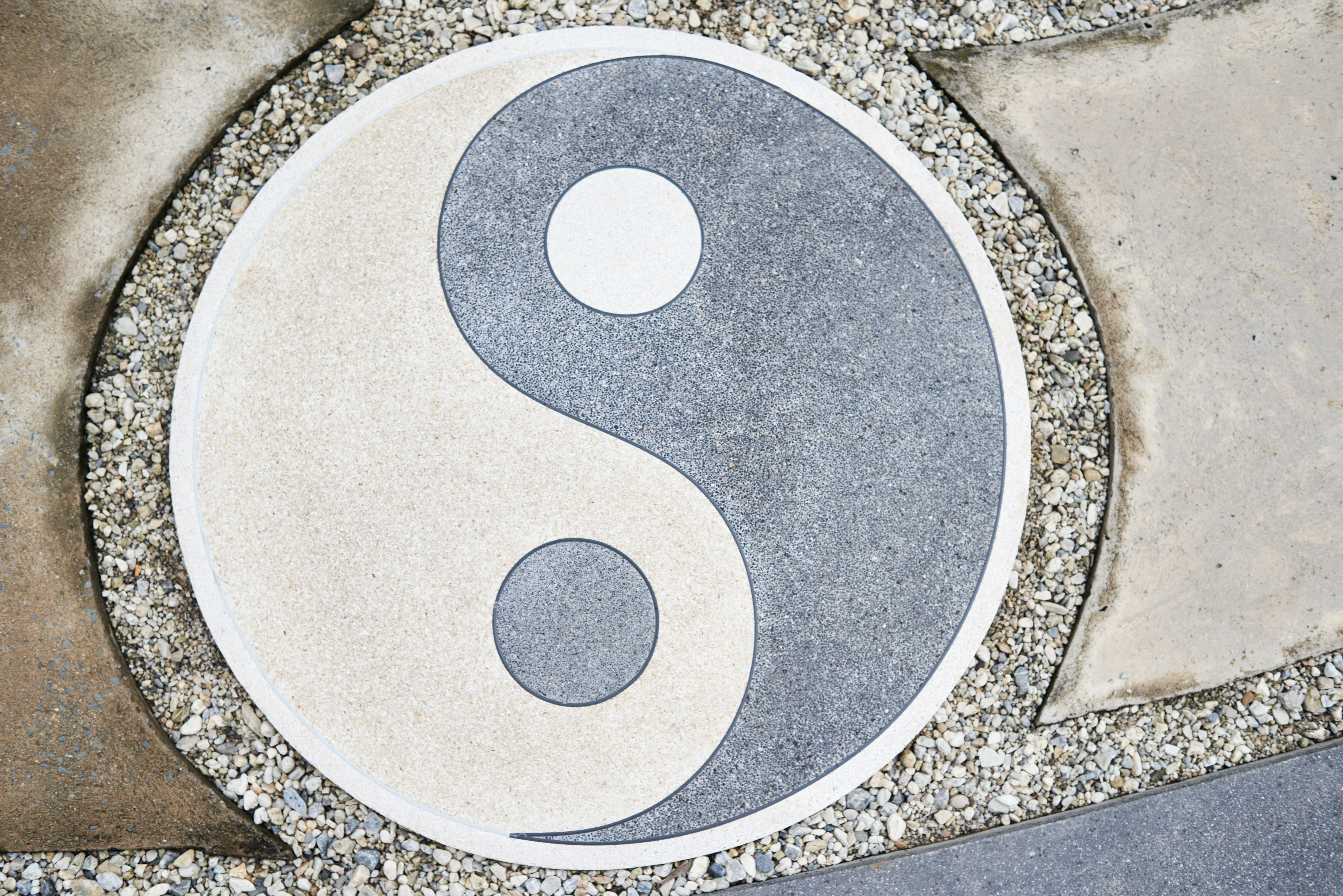 Yin-yang symbol embedded in gravel, representing balance and harmony