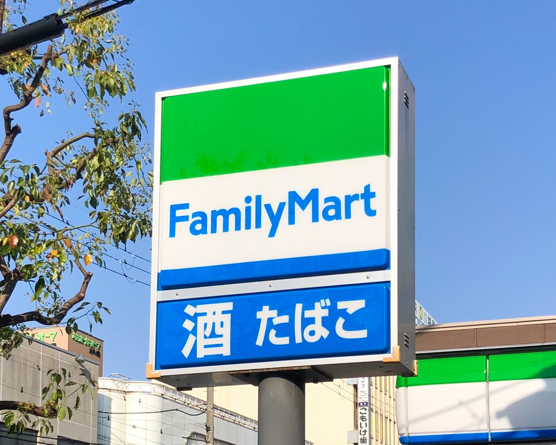 FamilyMartの看板。酒・たばこと書かれている。店舗が背景に見える。